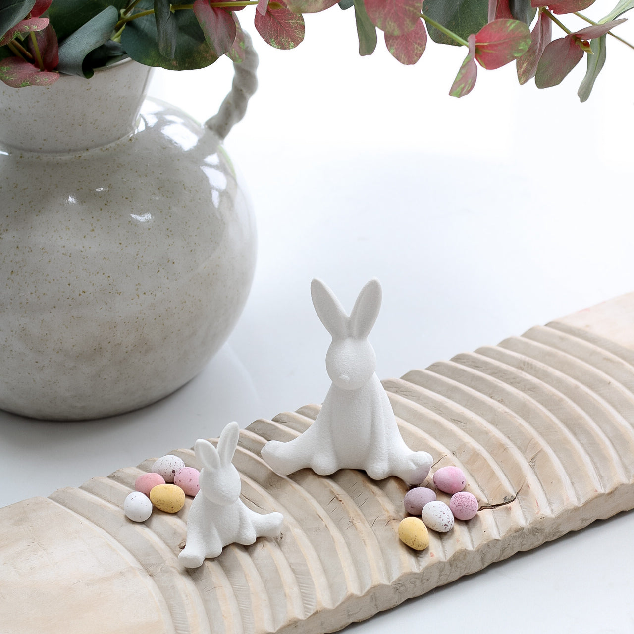 a large and small matt white ceramic bunny sat on a vintage washboard
