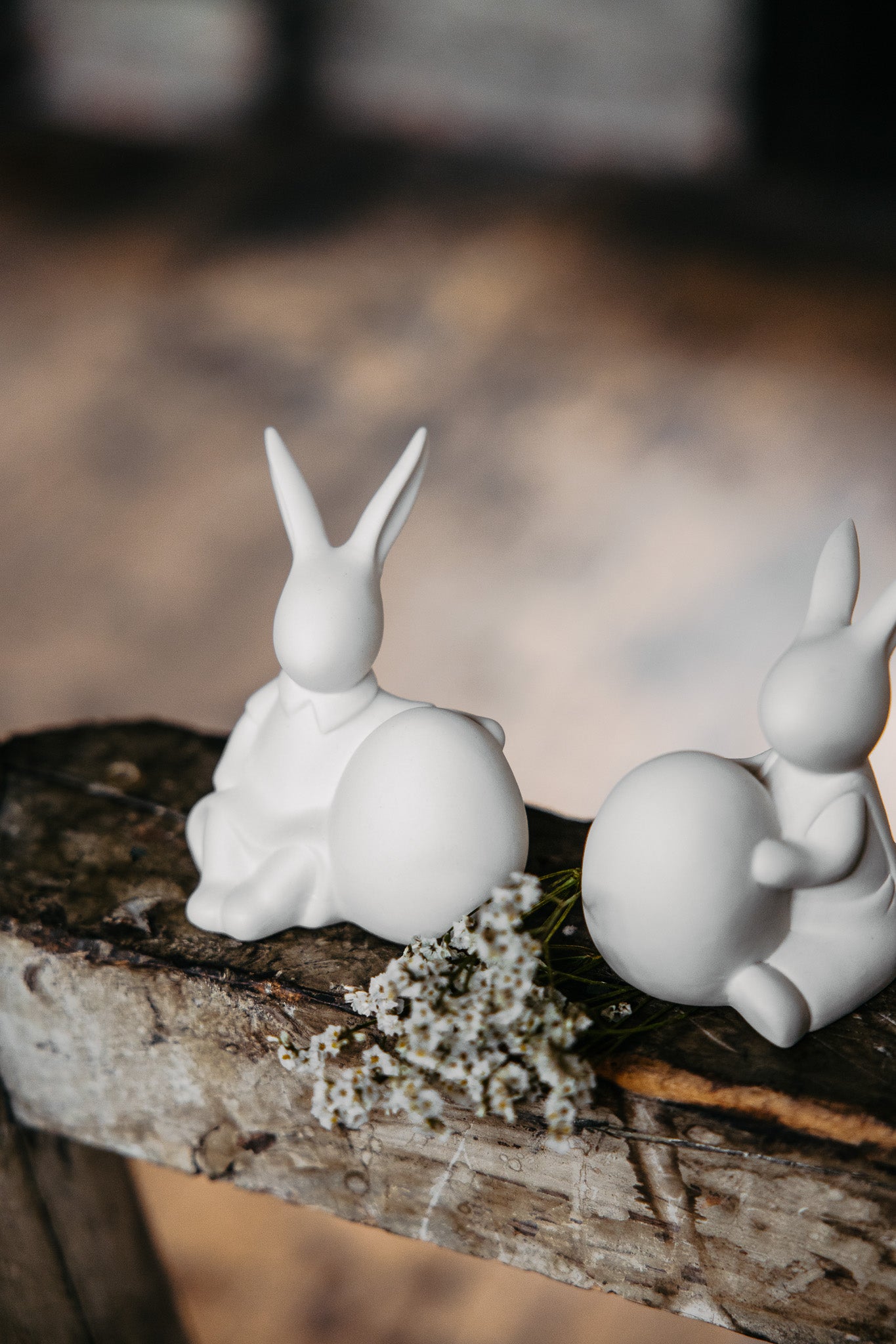 pair of ceramic white bunnies set on rustic wooden ledge