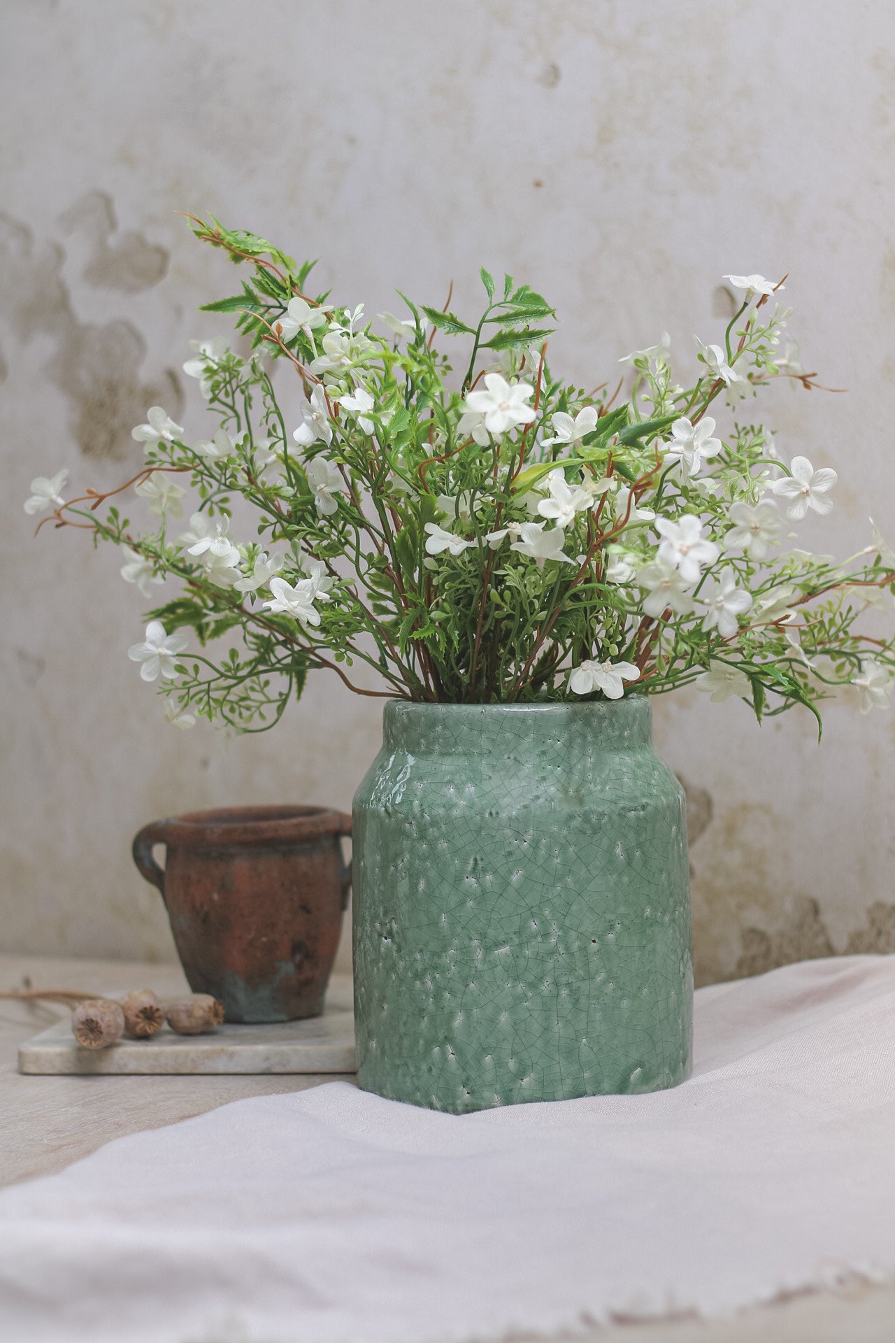 rustic green vase with faux green and white flowers