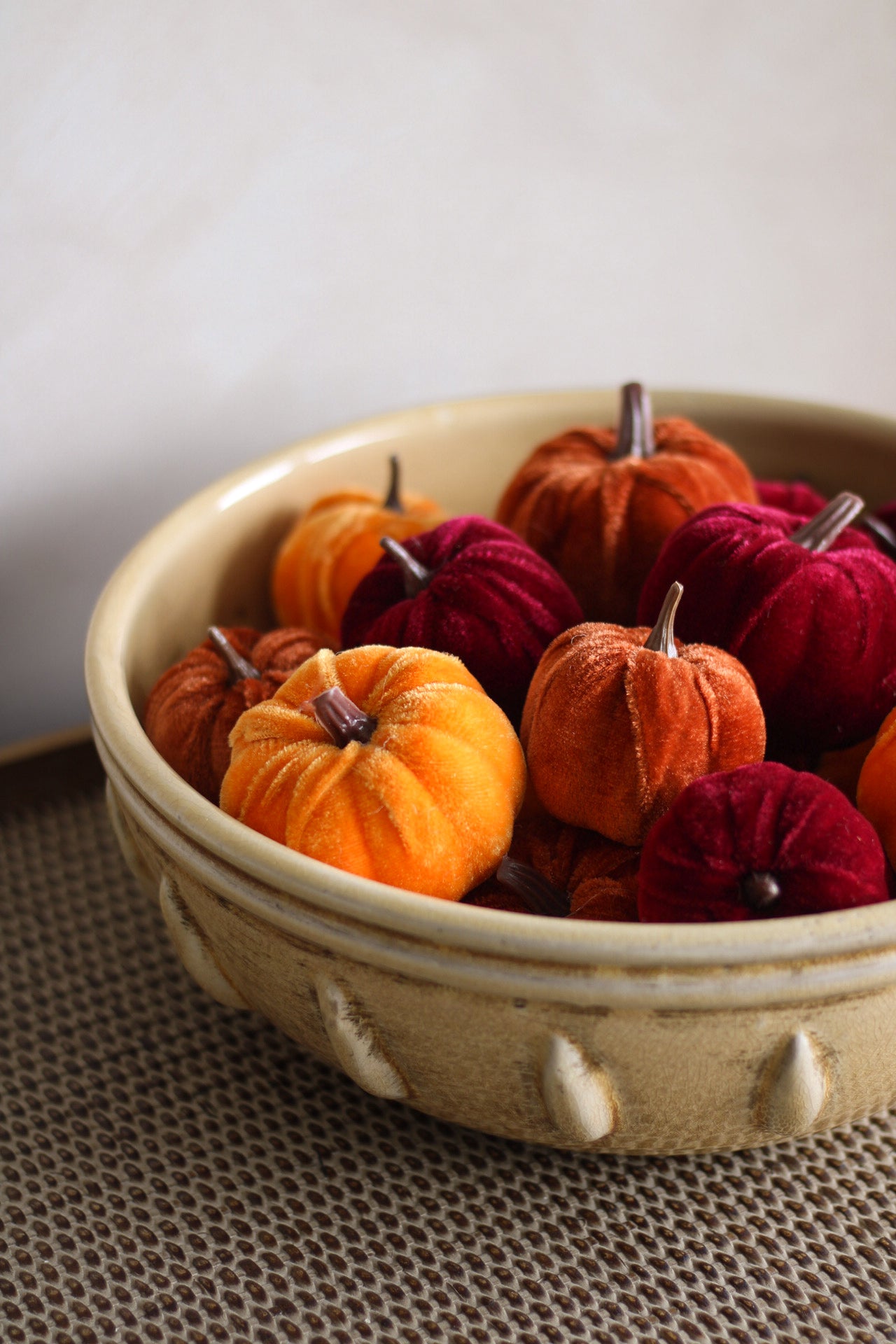 Decorative bowl with orange and red pumpkins on a textured surface