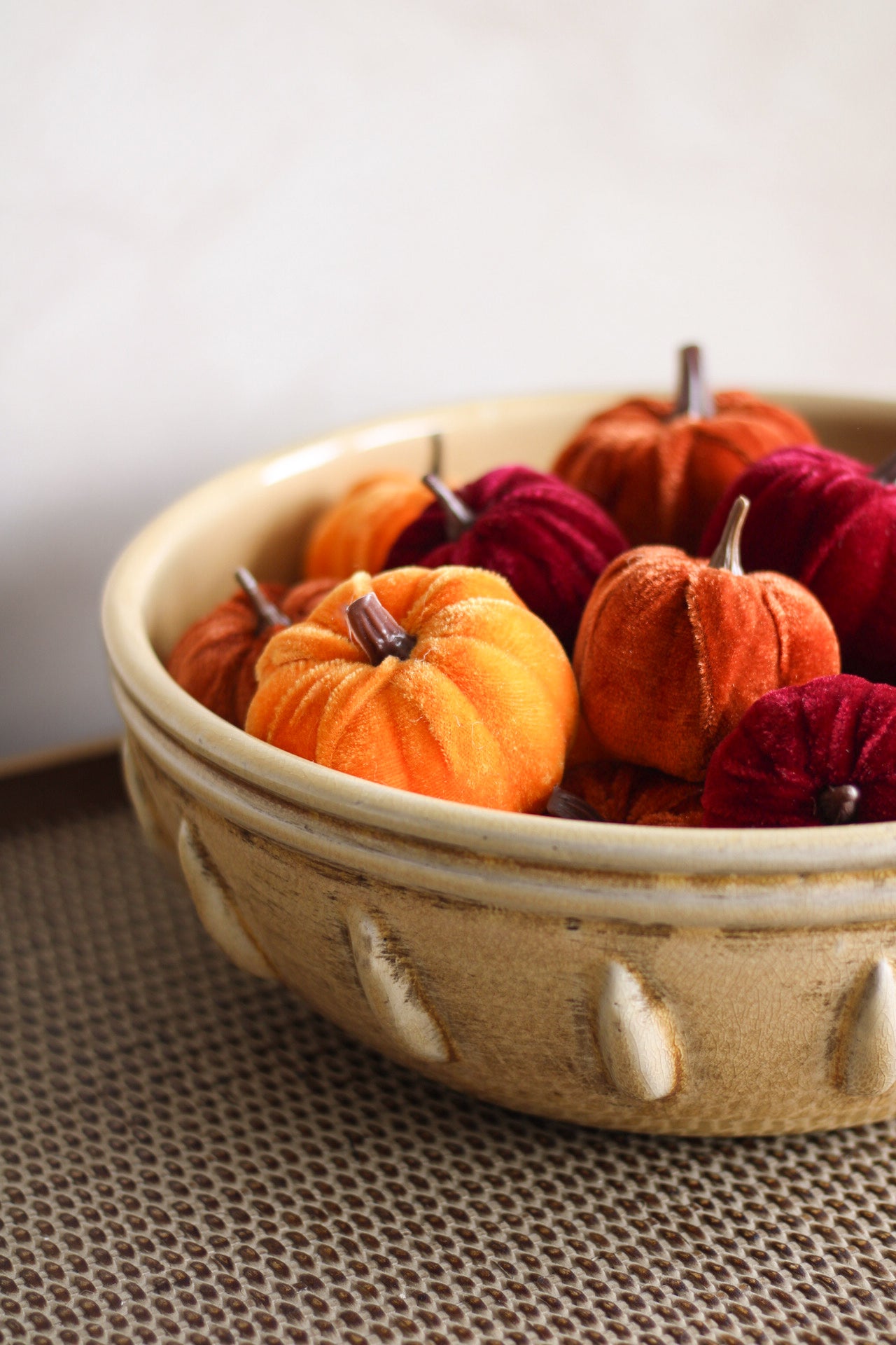 Decorative bowl with small pumpkins and gourds on a textured surface