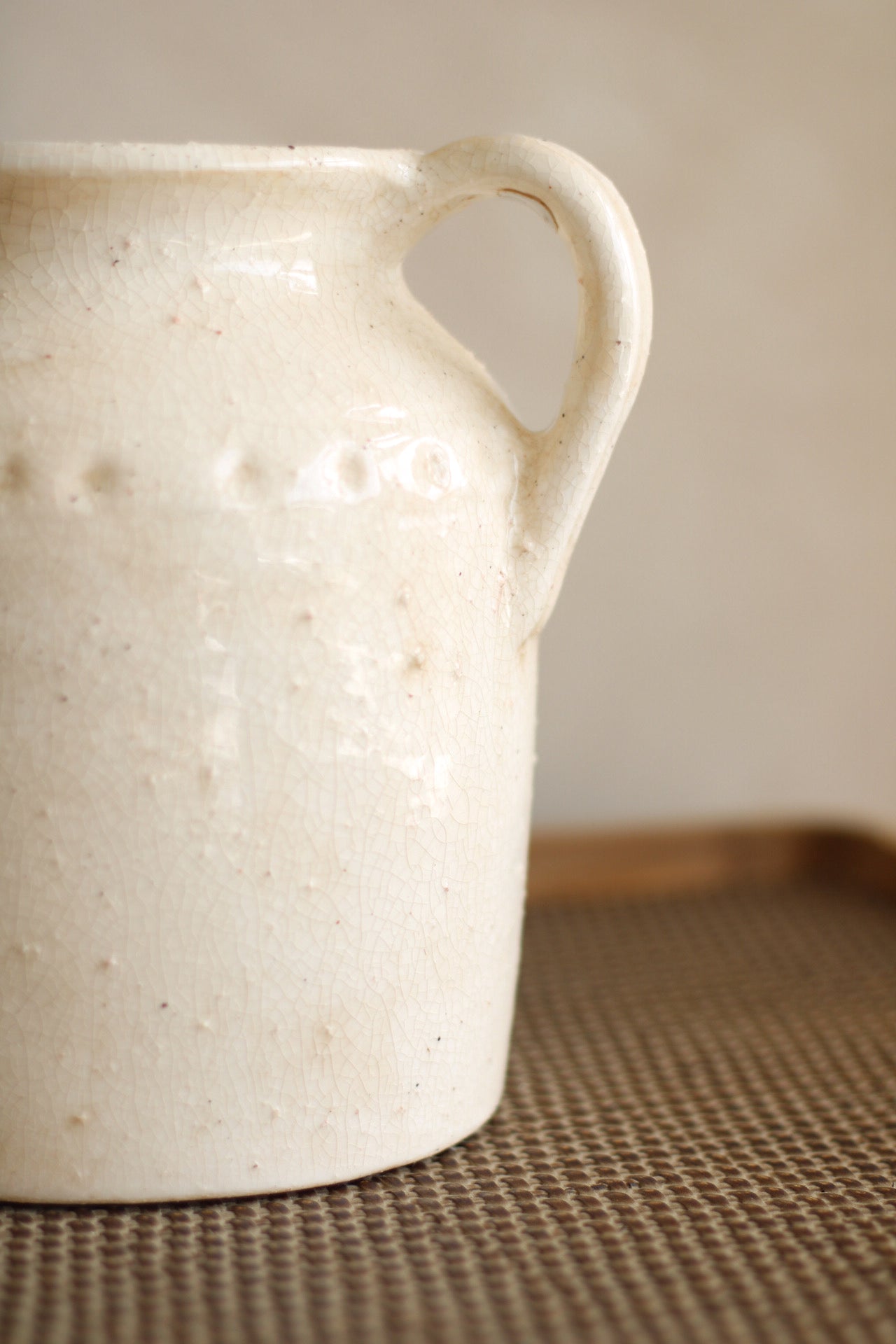 White ceramic pitcher on a textured surface with a neutral background