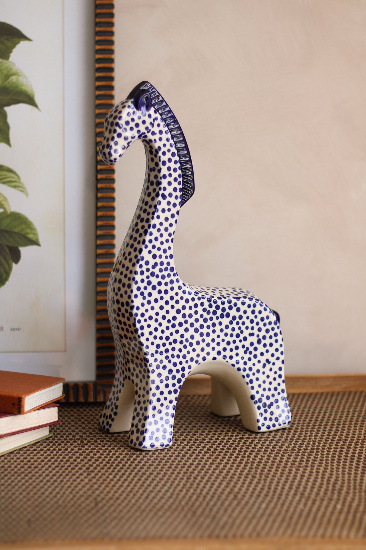 Decorative giraffe figurine with blue and white pattern on a beige wall and textured floor.