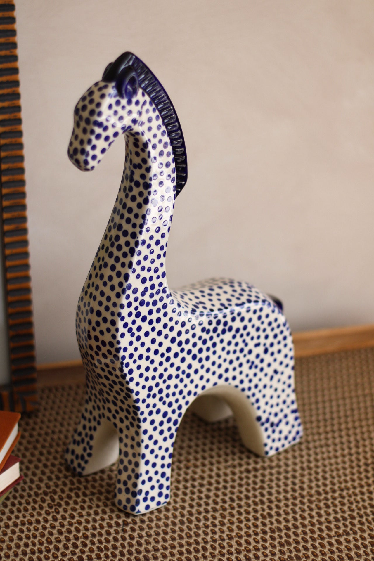 Decorative ceramic giraffe with blue and white pattern on a textured surface.