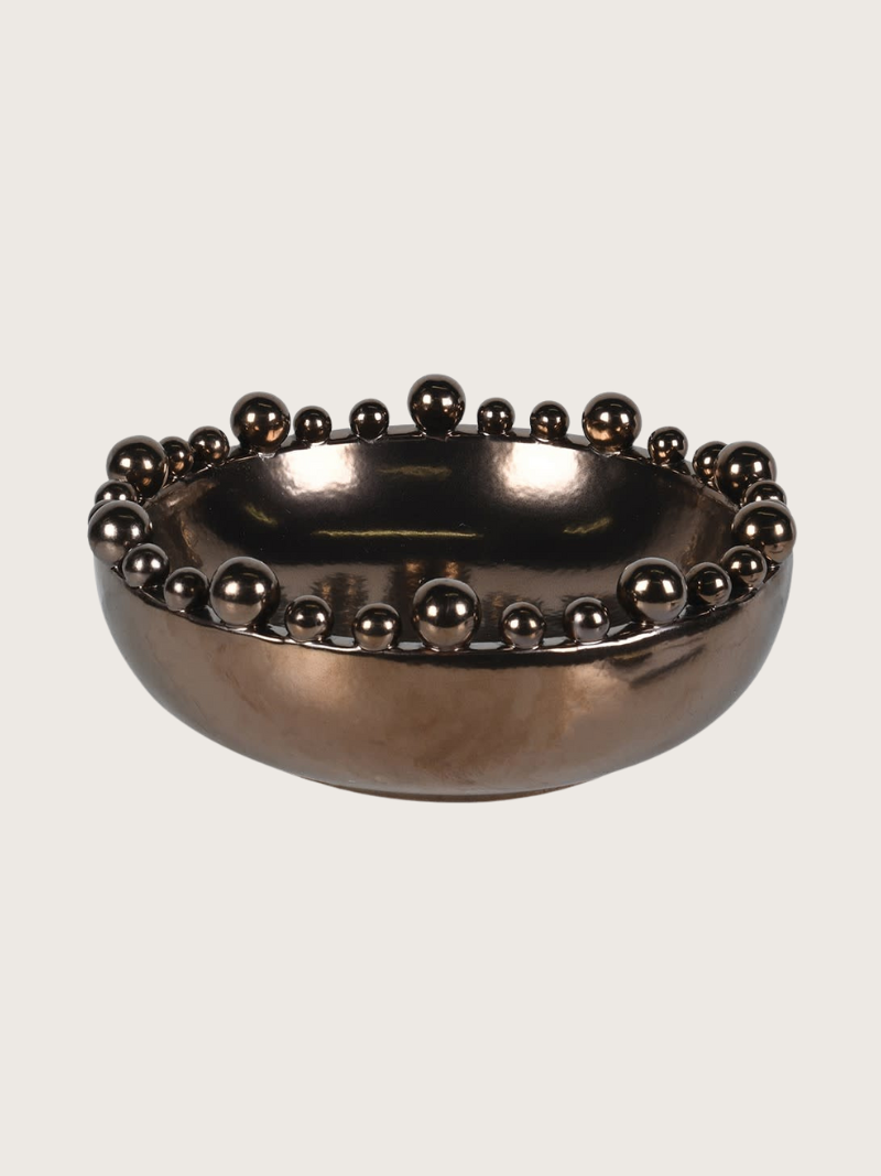 Bronze bowl with bobble embellishments on a light gray background