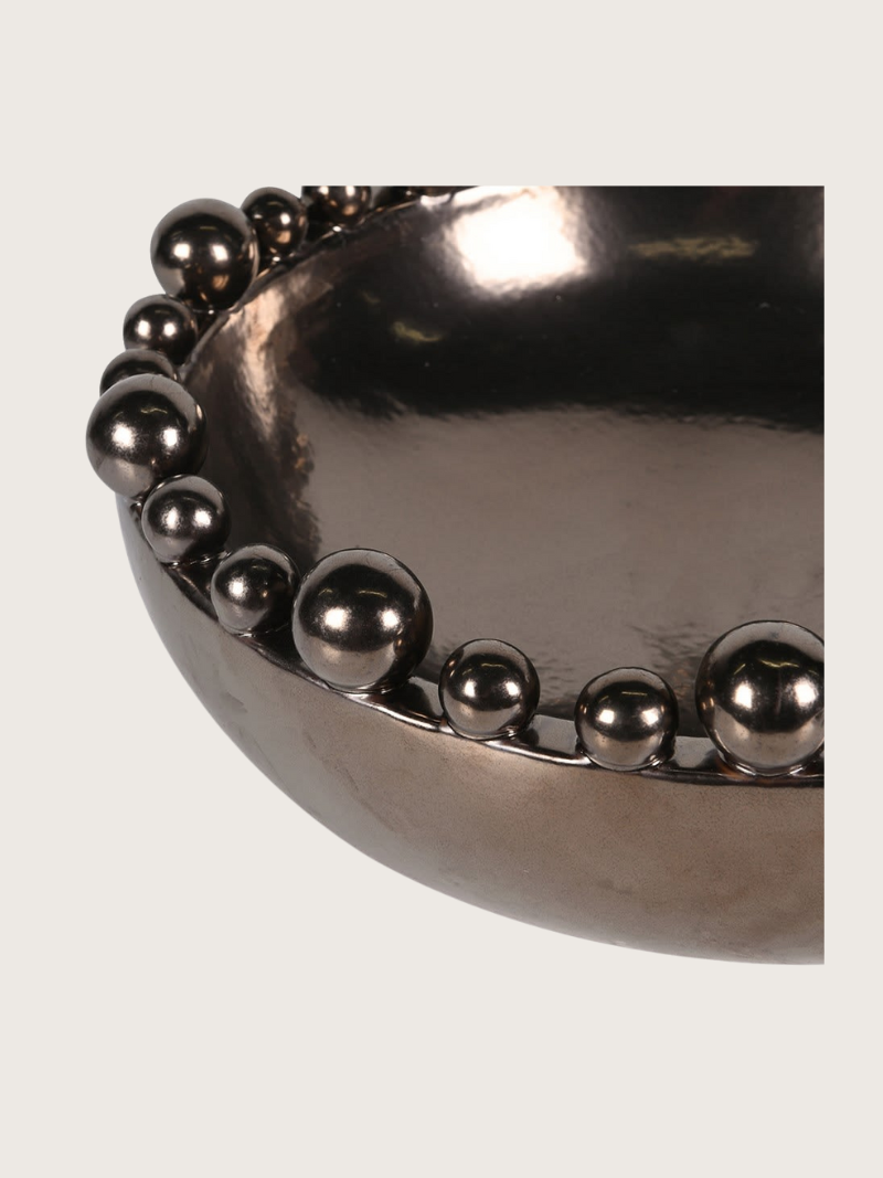 Metallic bronze bowl with spherical embellishments on a light gray background