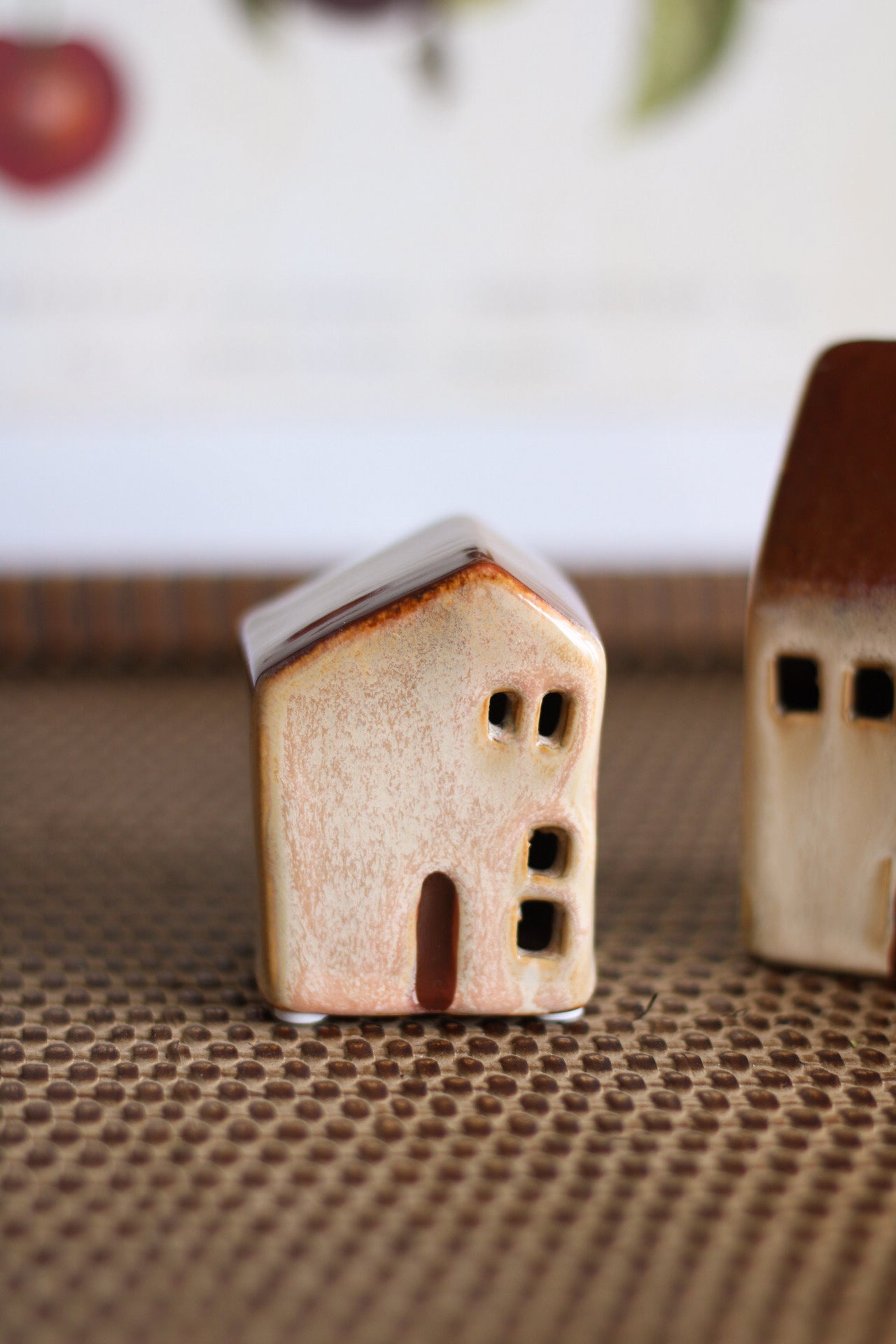 Two small ceramic houses on a textured surface with a blurred background