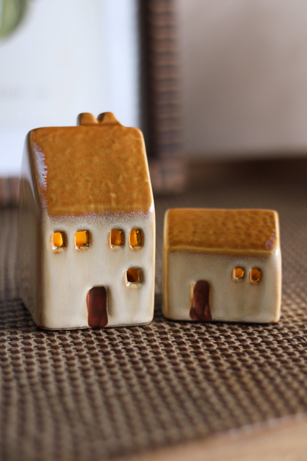 Two ceramic house-shaped figurines on a textured surface