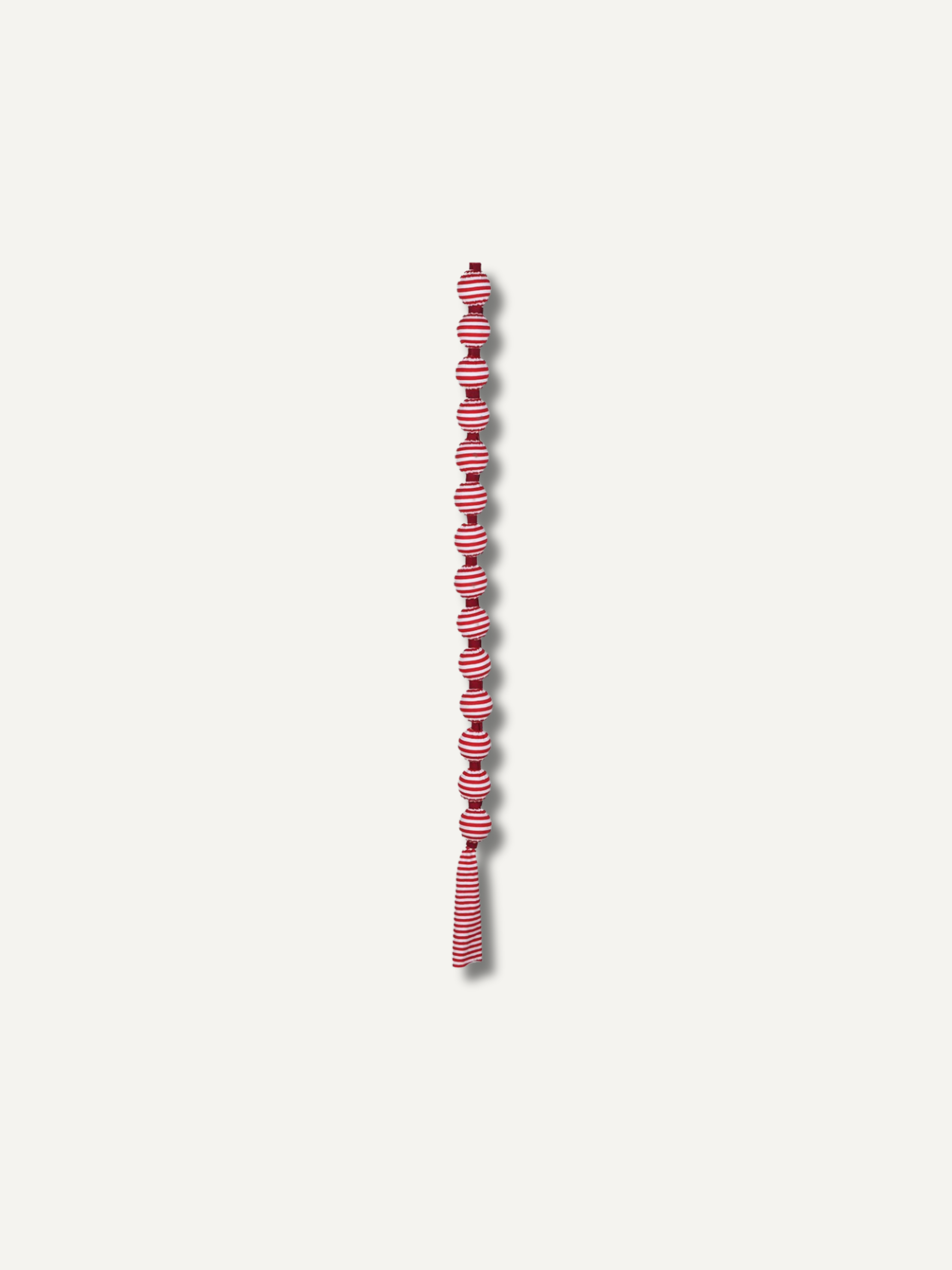 A long, narrow decorative garland or tassel strand with alternating candy cane red and white striped knotted sections, centered on a plain light gray background.