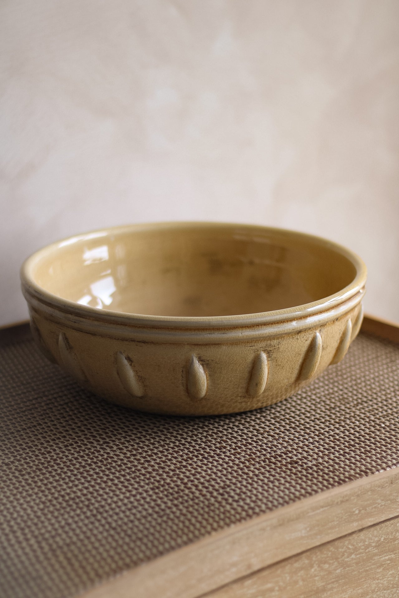 Mustard ceramic bowl on a textured surface with a neutral background