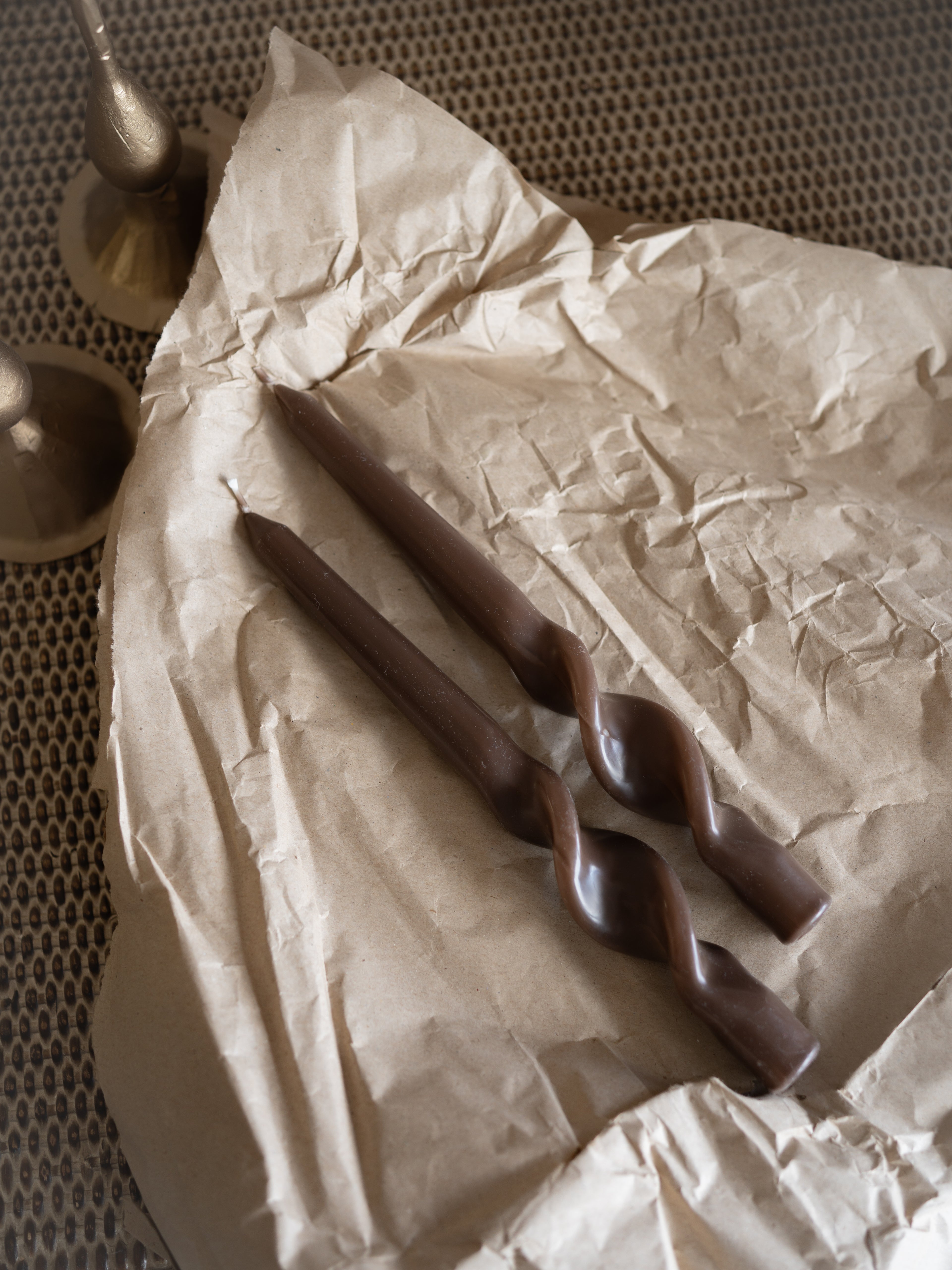 caramel dinner candles on crumpled brown paper with a textured background