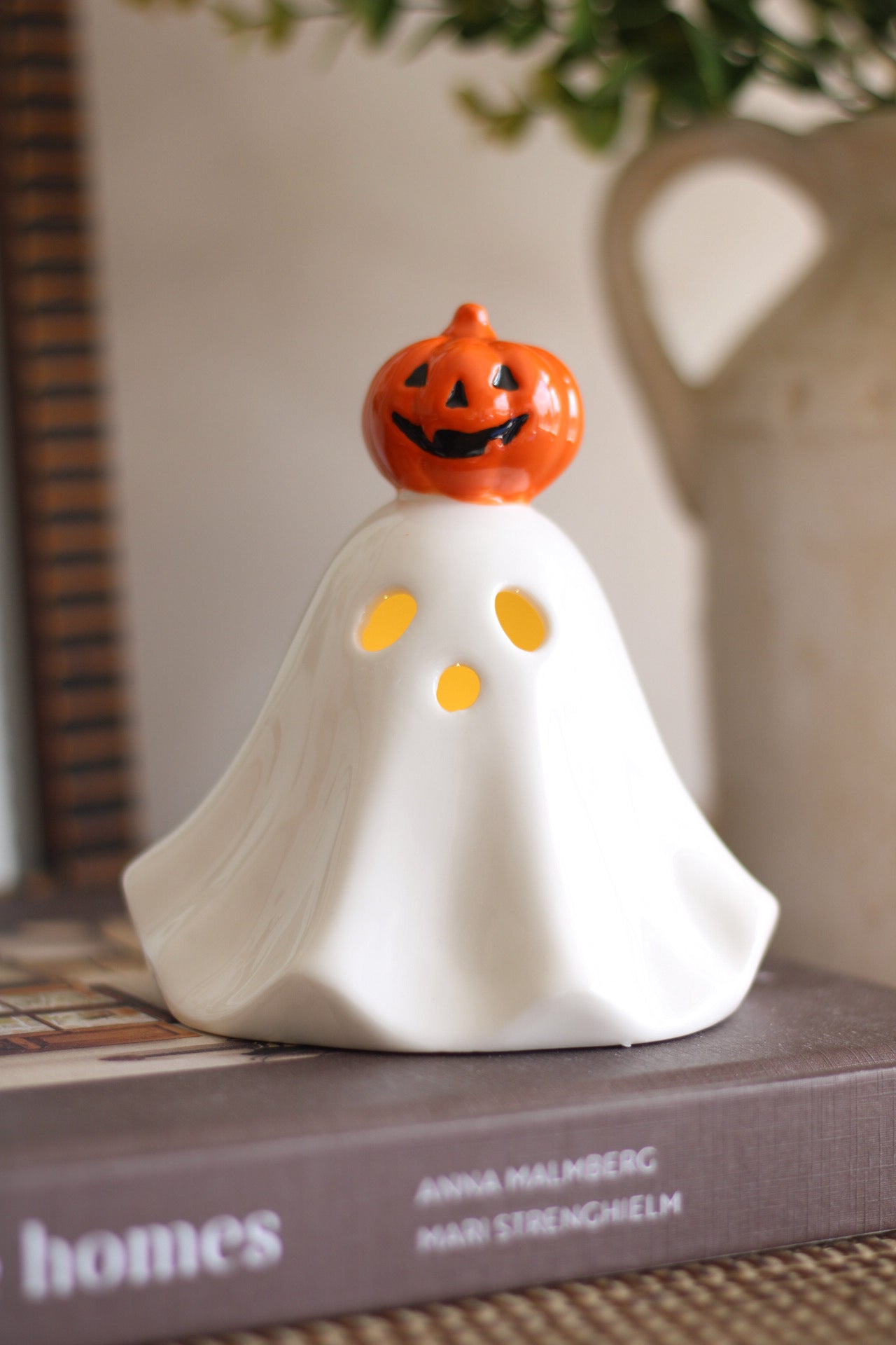 Ghost-shaped decorative item with a pumpkin head on a book