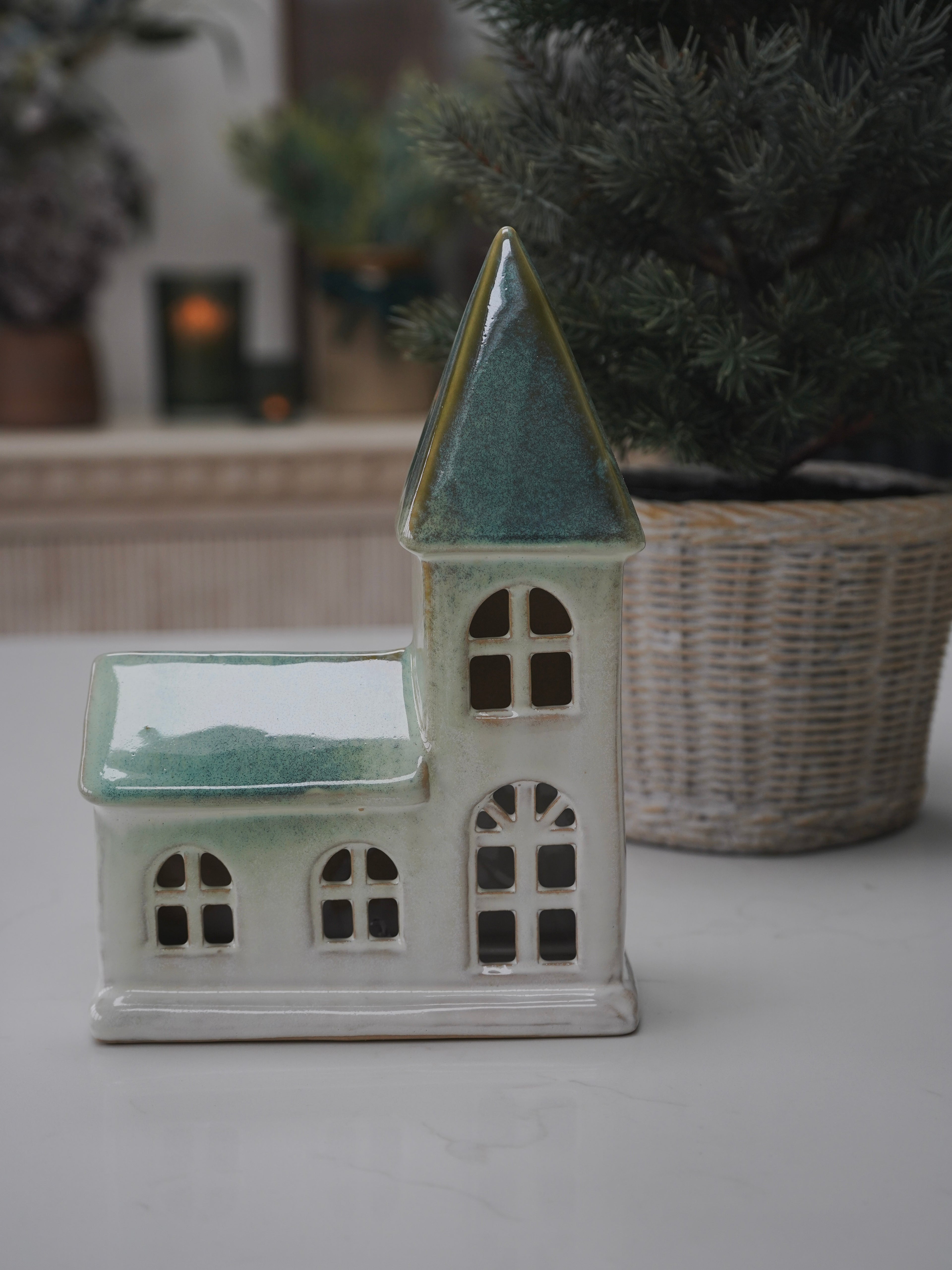 Small ceramic church with a green roof on a white surface