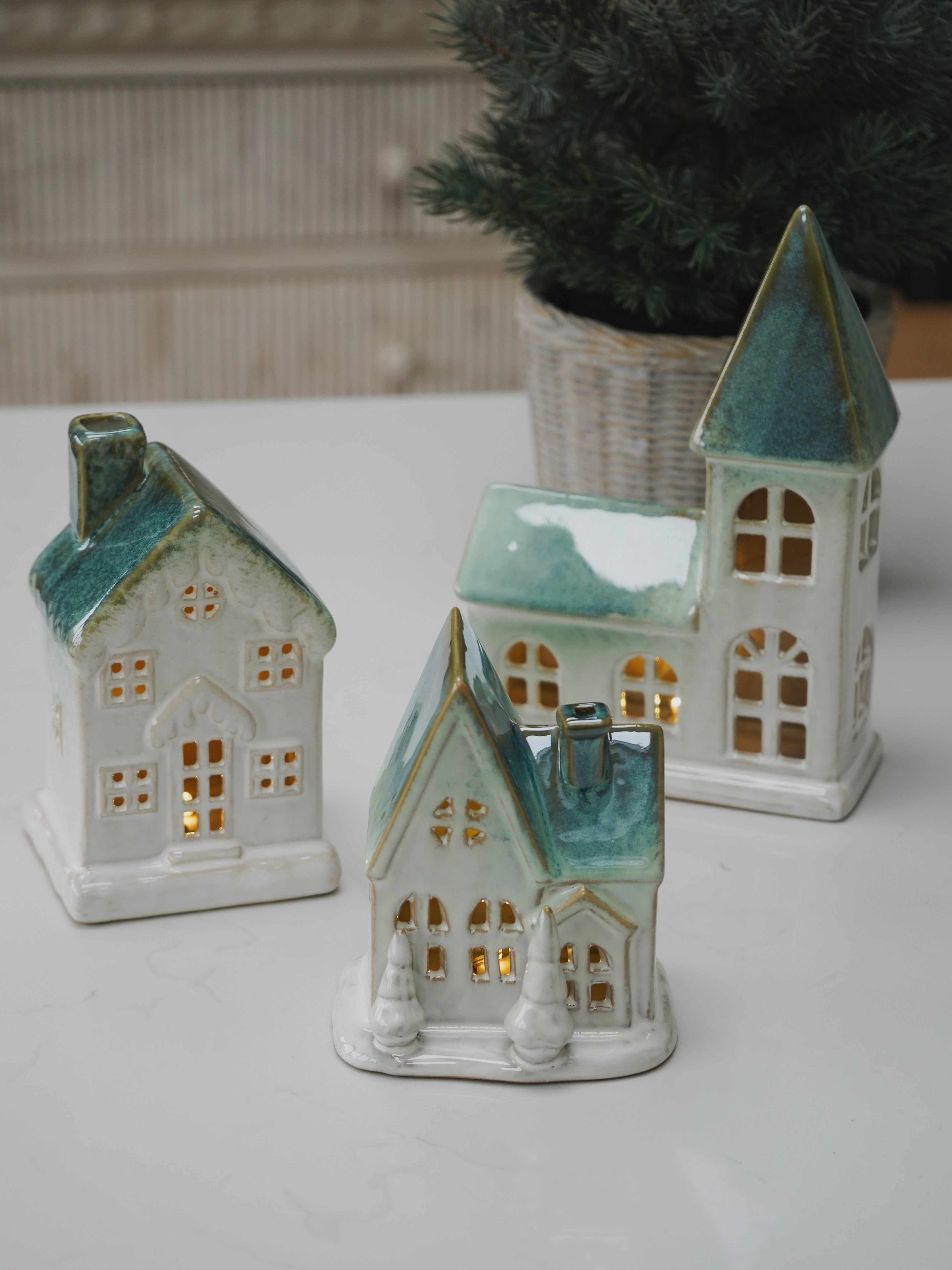 Set of ceramic house-shaped lanterns on a white surface with a blurred background