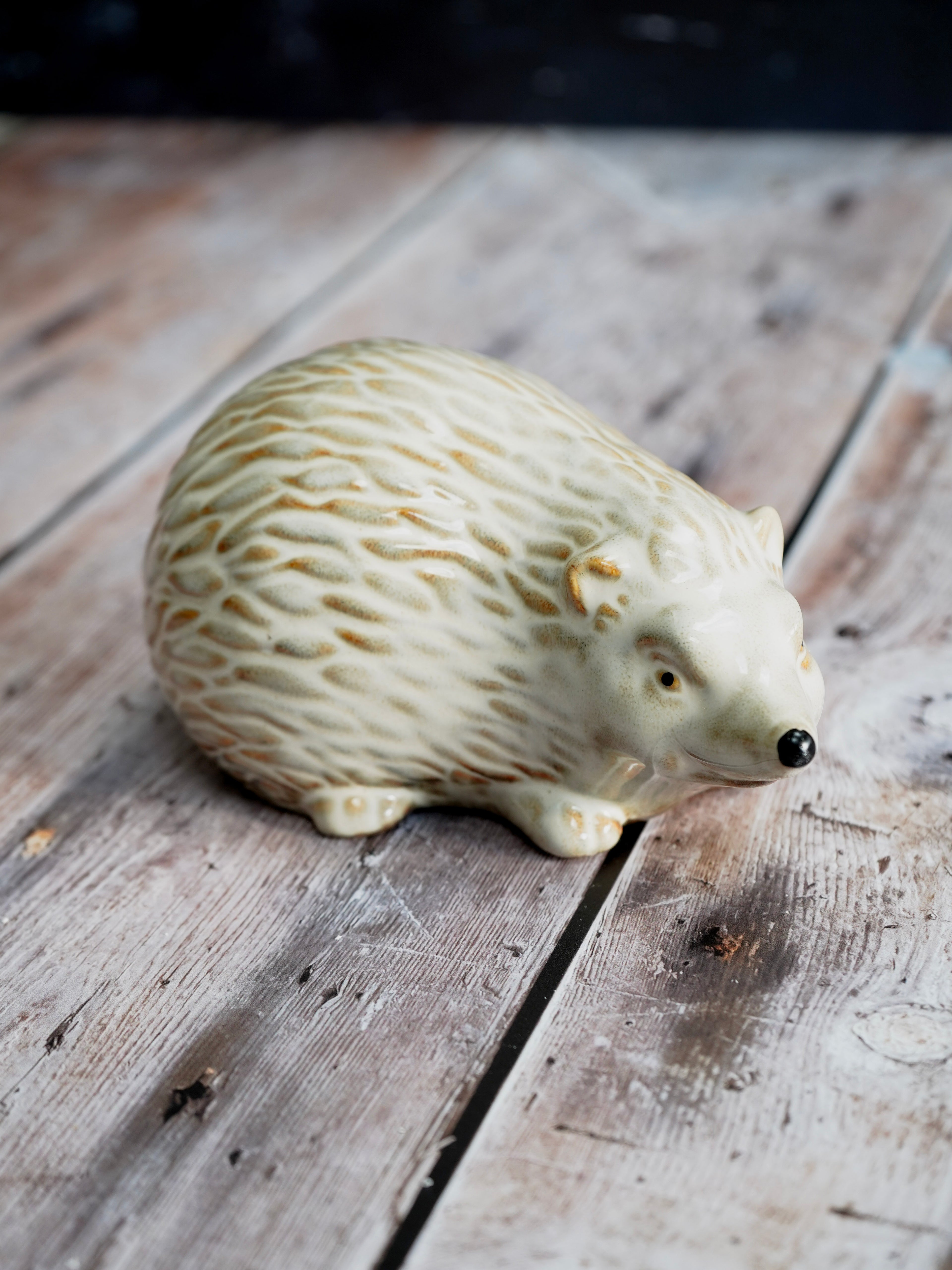 White ceramic hedgehog figurine on a wooden surface