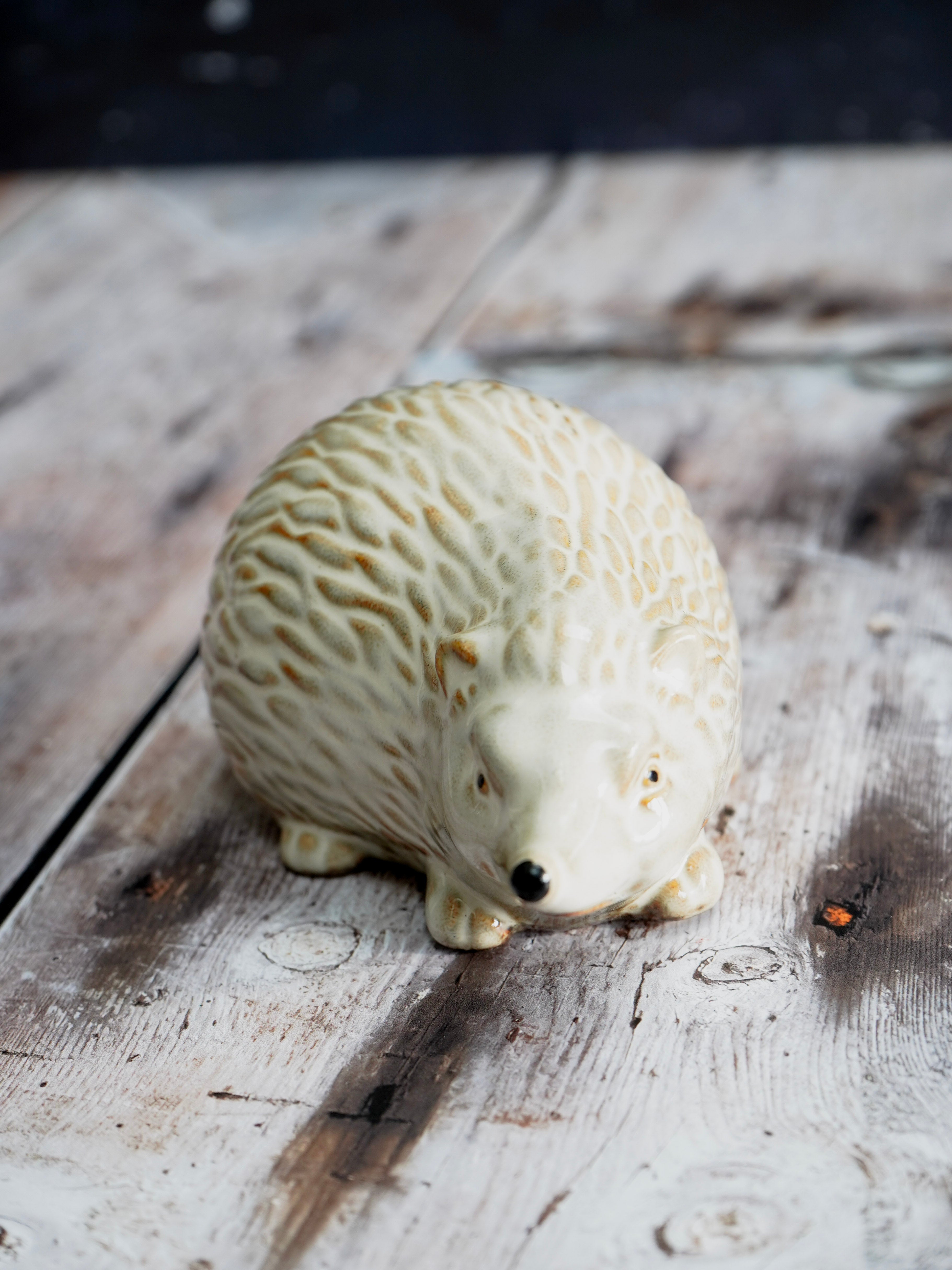 White ceramic hedgehog figurine on a wooden surface
