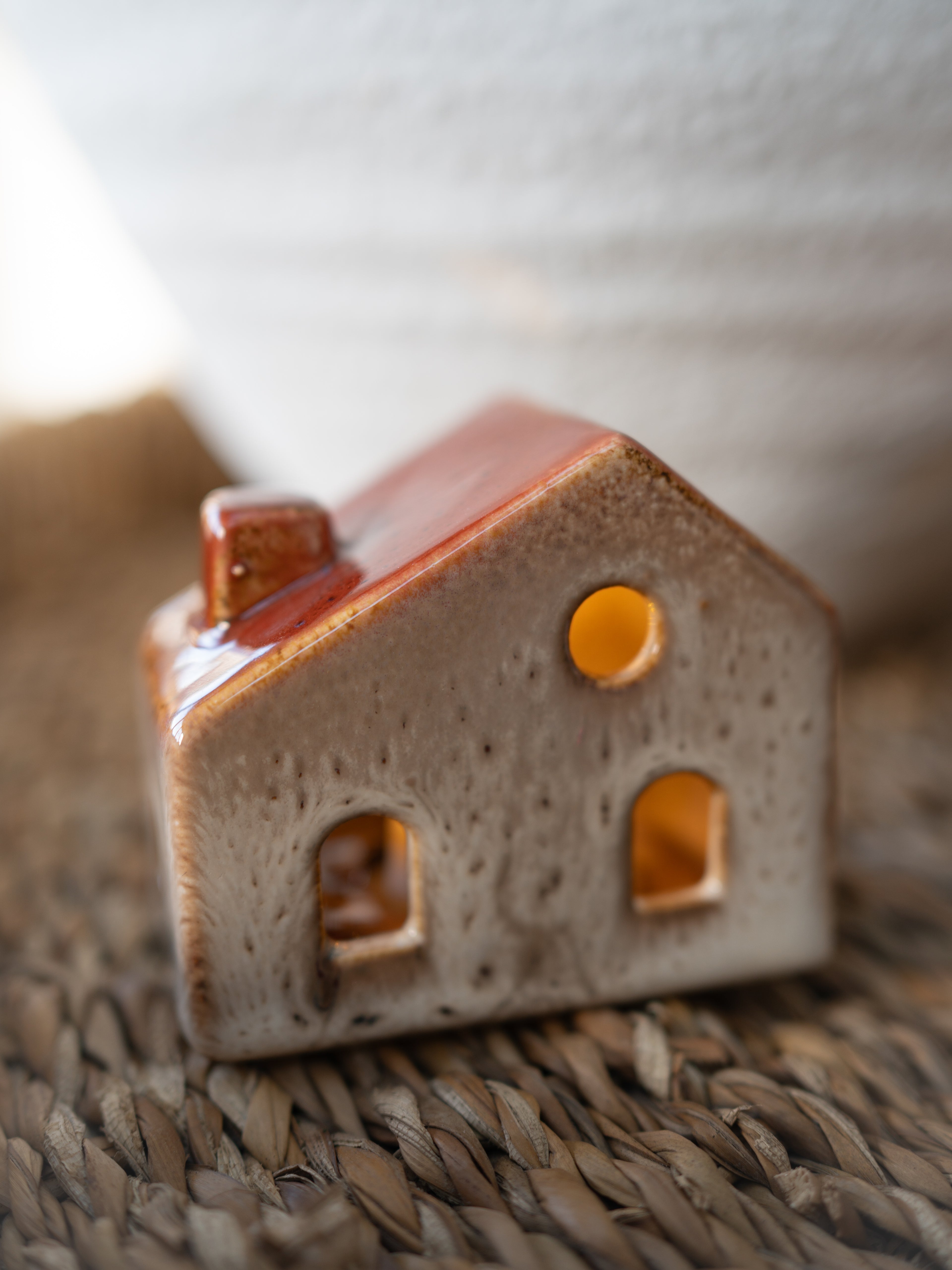 Small ceramic house-shaped object on a woven surface