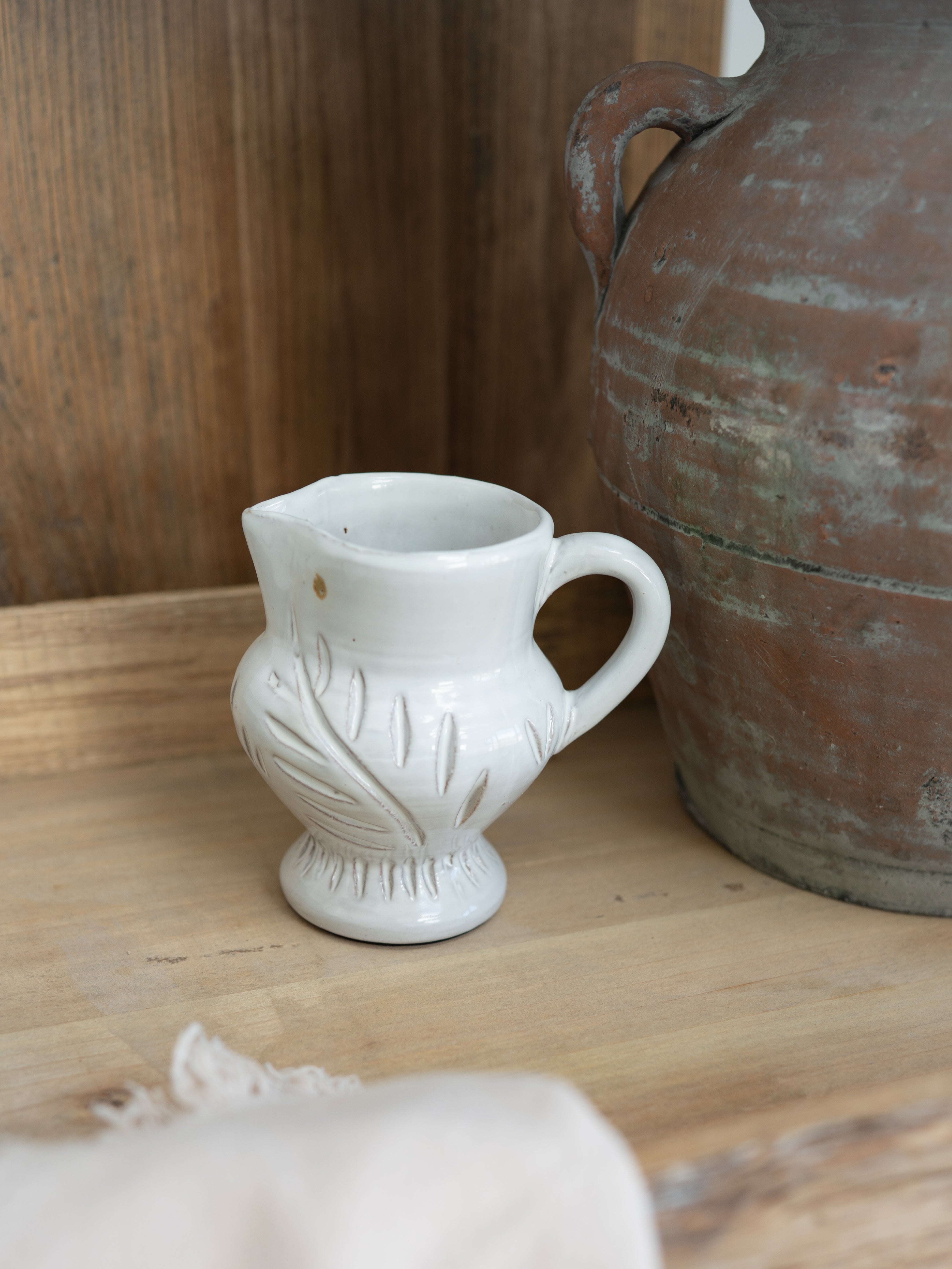 White ceramic White Leaf etched jug with decorative design on a wooden surface