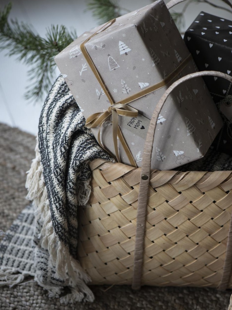 Gift basket with wrapped presents and a blanket on a textured surface