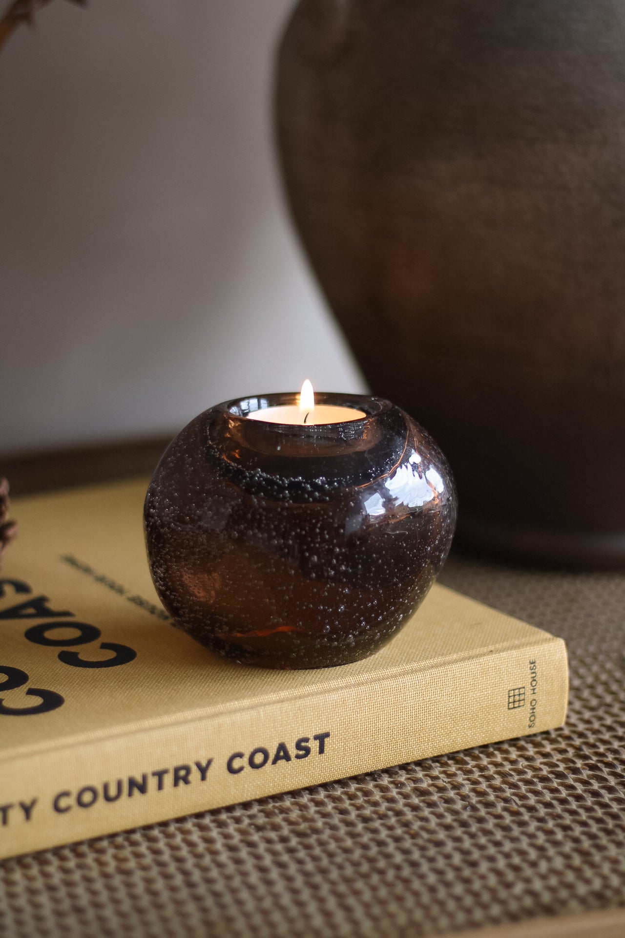 Candle in a brown glass holder on a book titled &