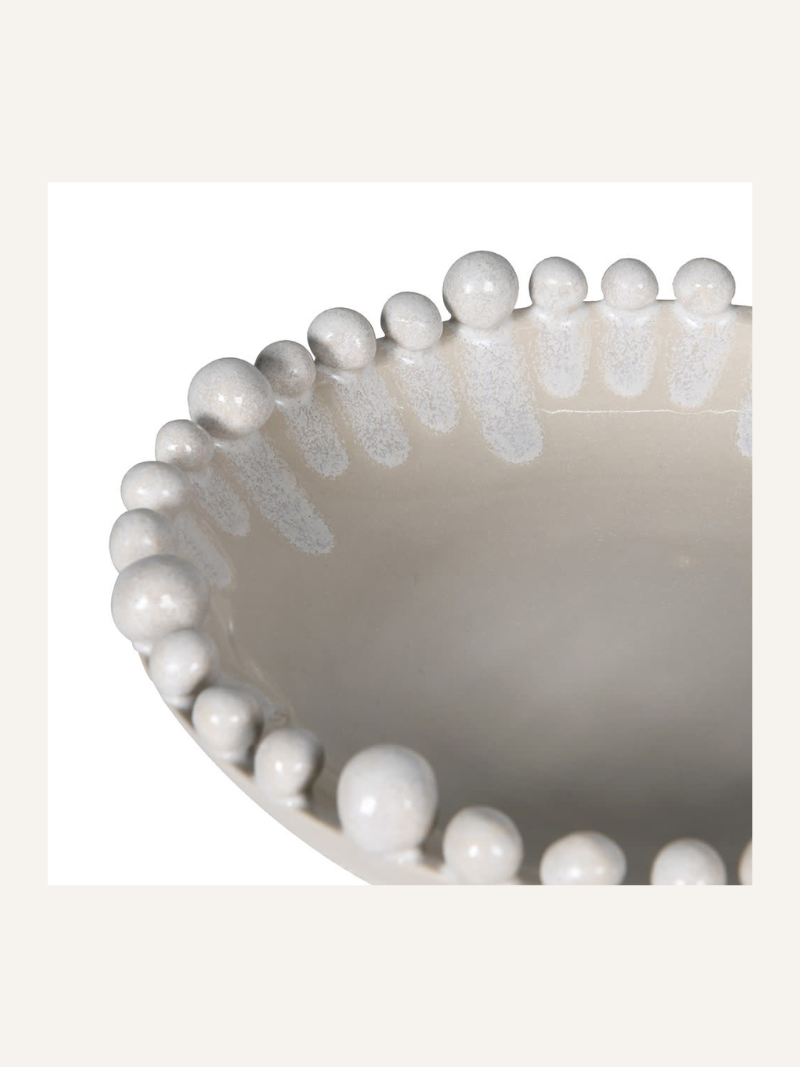 Close-up of a decorative bowl with bobble-like beads on a white background