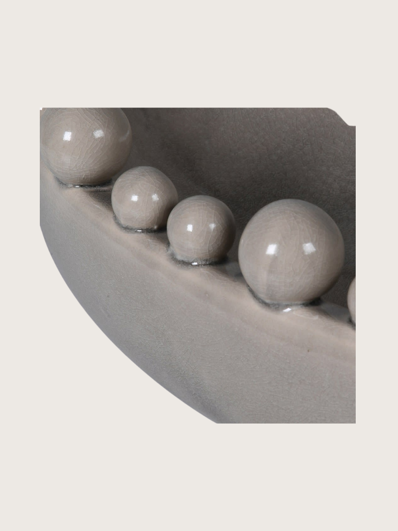 Row of cream ceramic bobbles on a curved decorative bowl