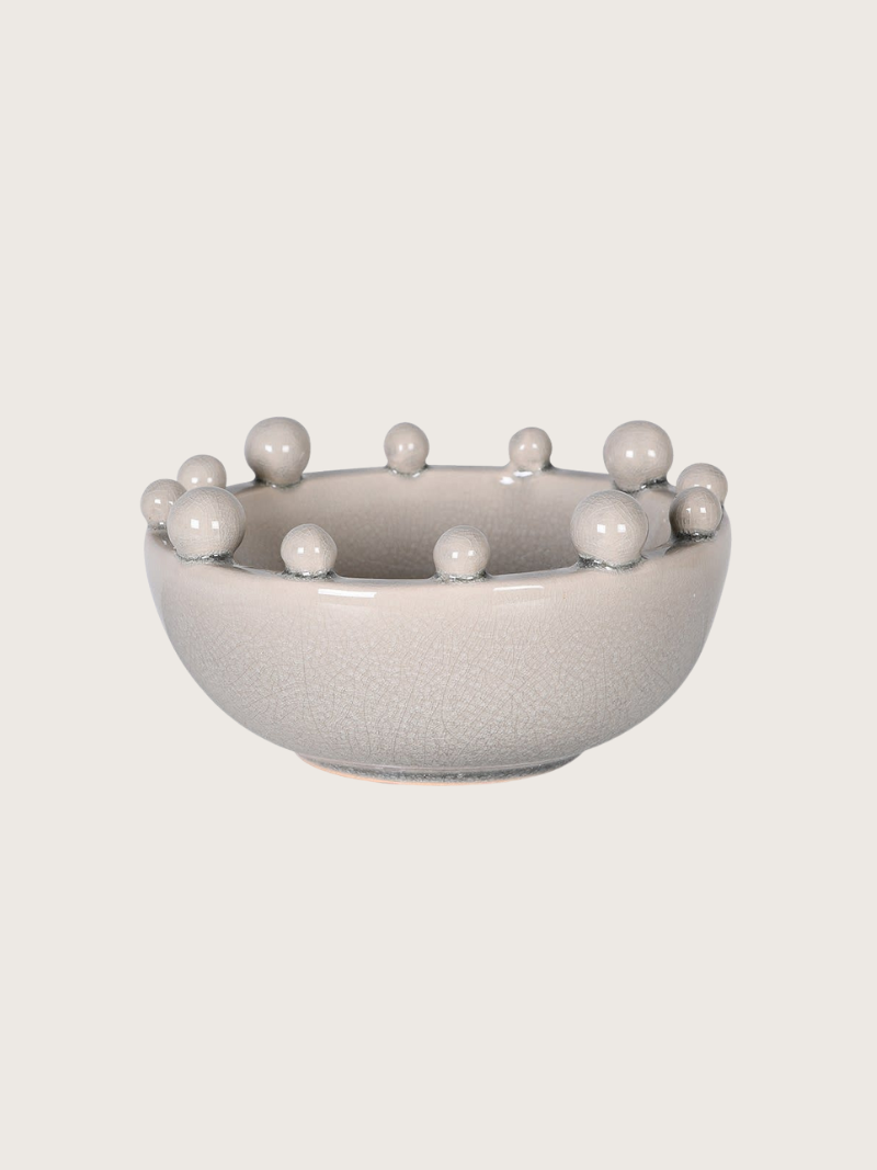Cream ceramic bowl with bobble protrusions on a light gray background