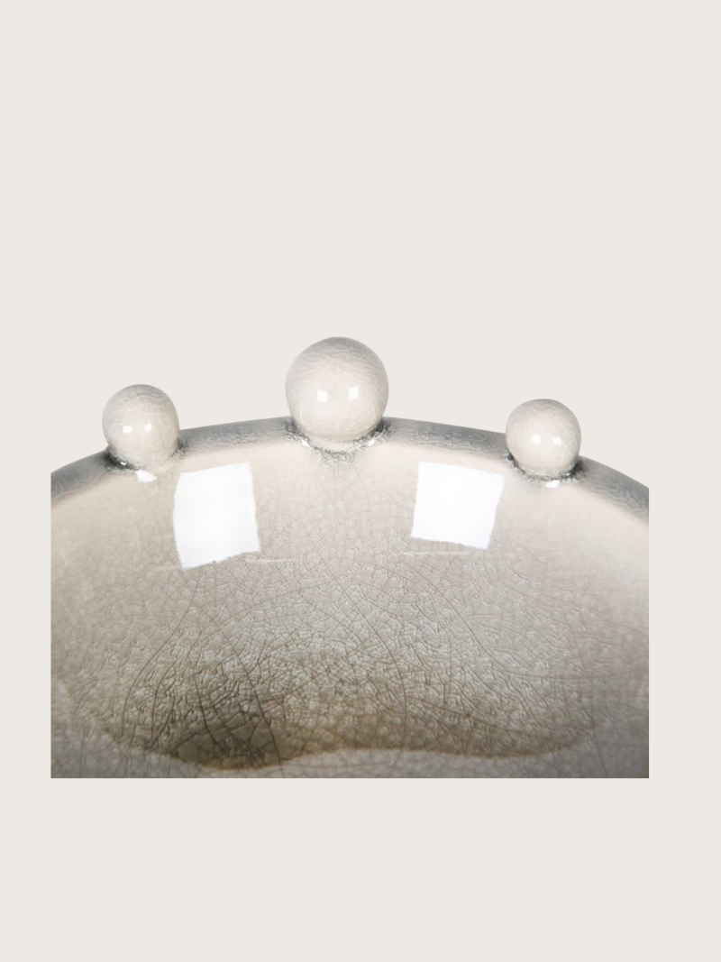 Ceramic bowl with a textured surface and spherical protrusions on a light gray background
