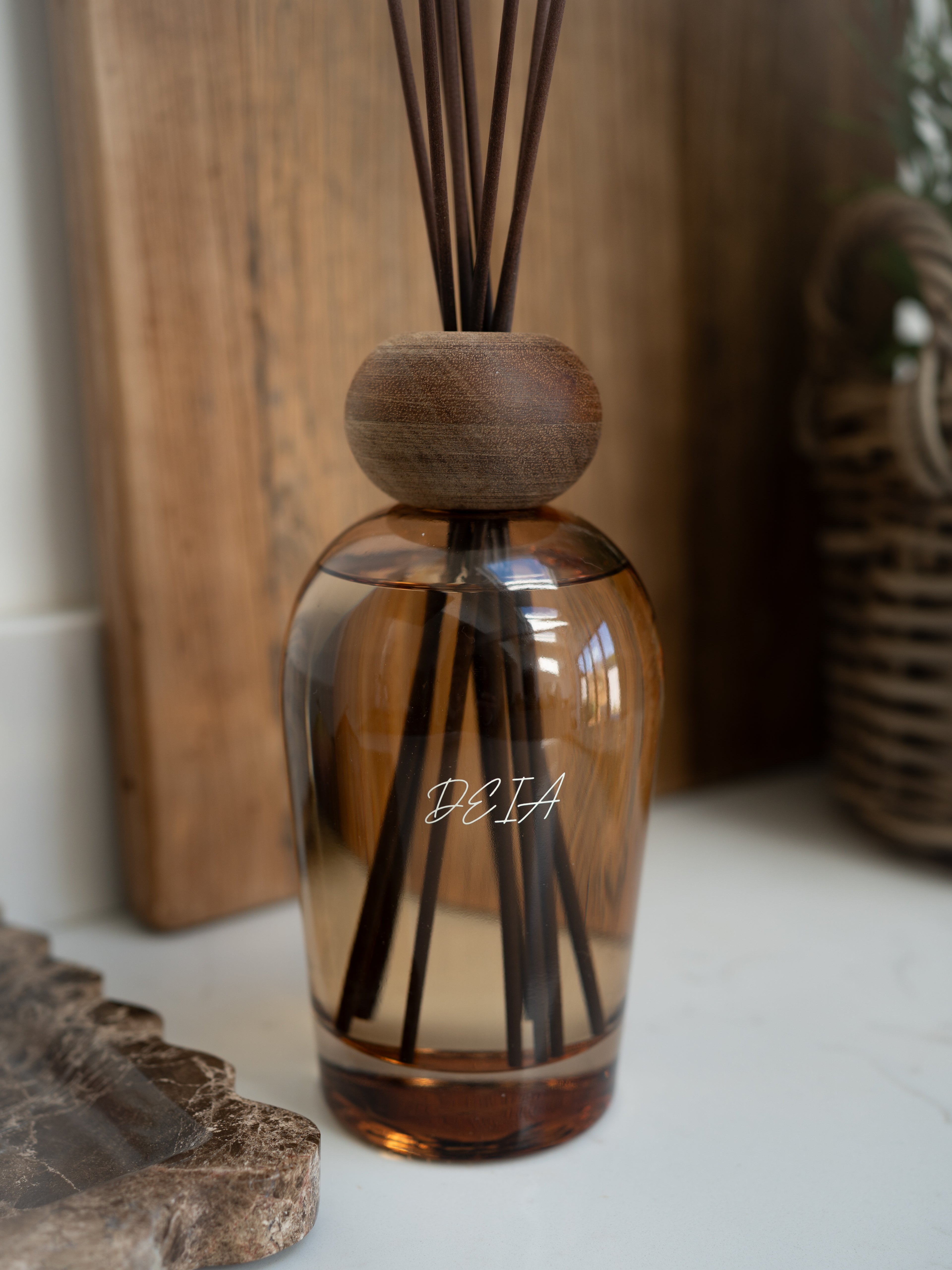 Brown glass diffuser bottle with wooden cap and reeds on a neutral background