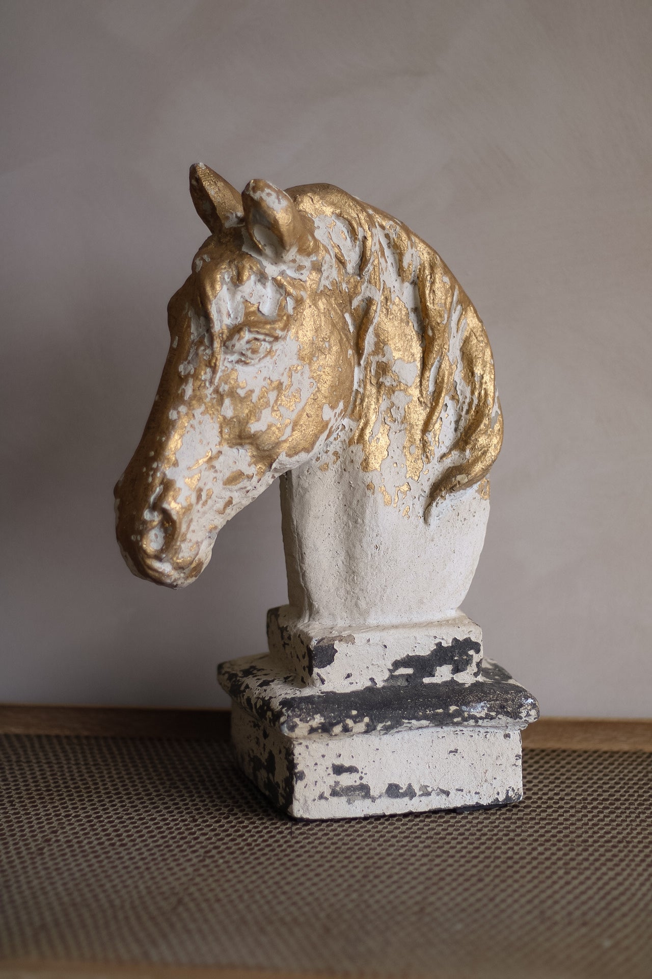 Decorative horse head sculpture with gold and white finish on a neutral background