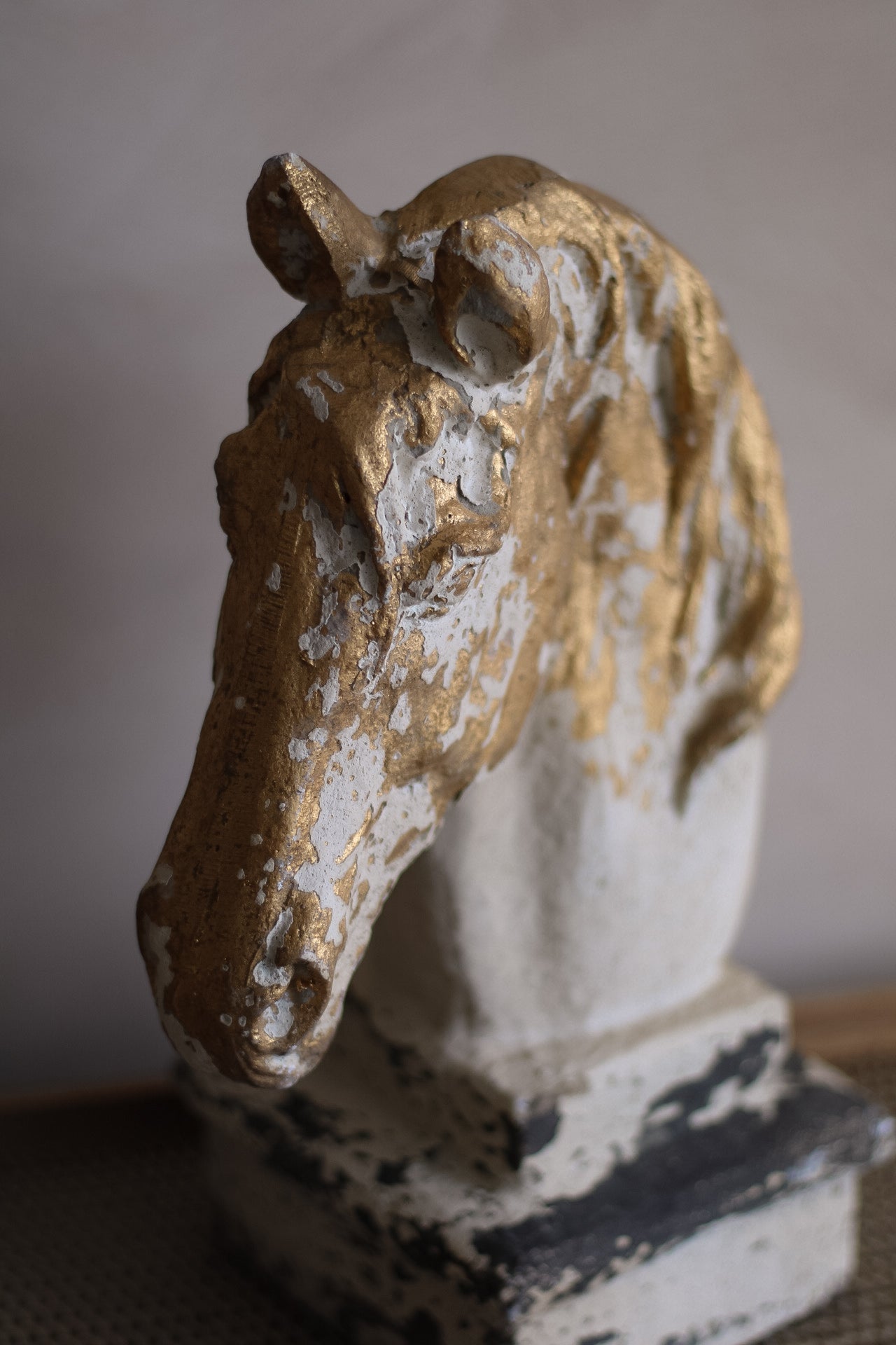 Decorative horse head sculpture with gold and white finish on a neutral background