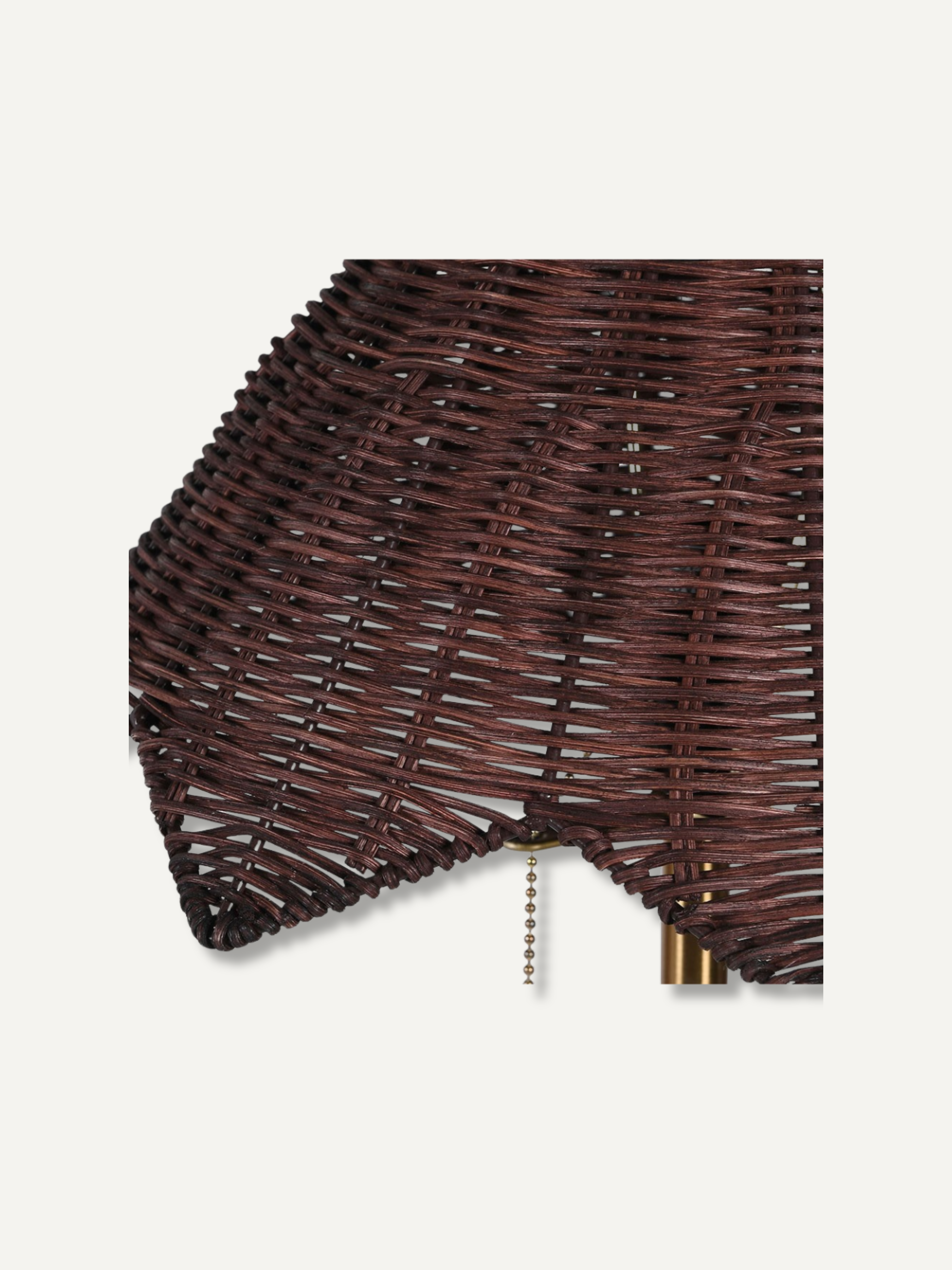 Close-up of a dark brown woven wicker or rattan lampshade with a triangular folded edge and a short hanging chain, shown on a plain light background.