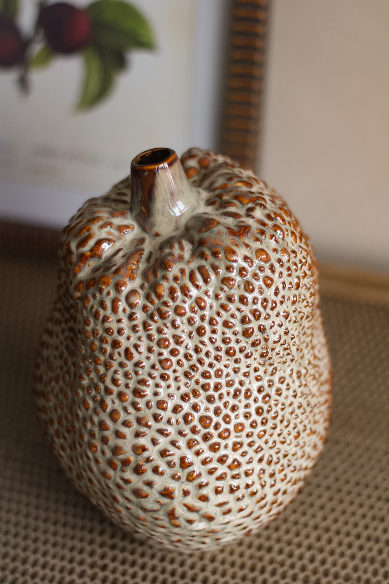 Ceramic vase with textured surface and brown accents on a neutral background