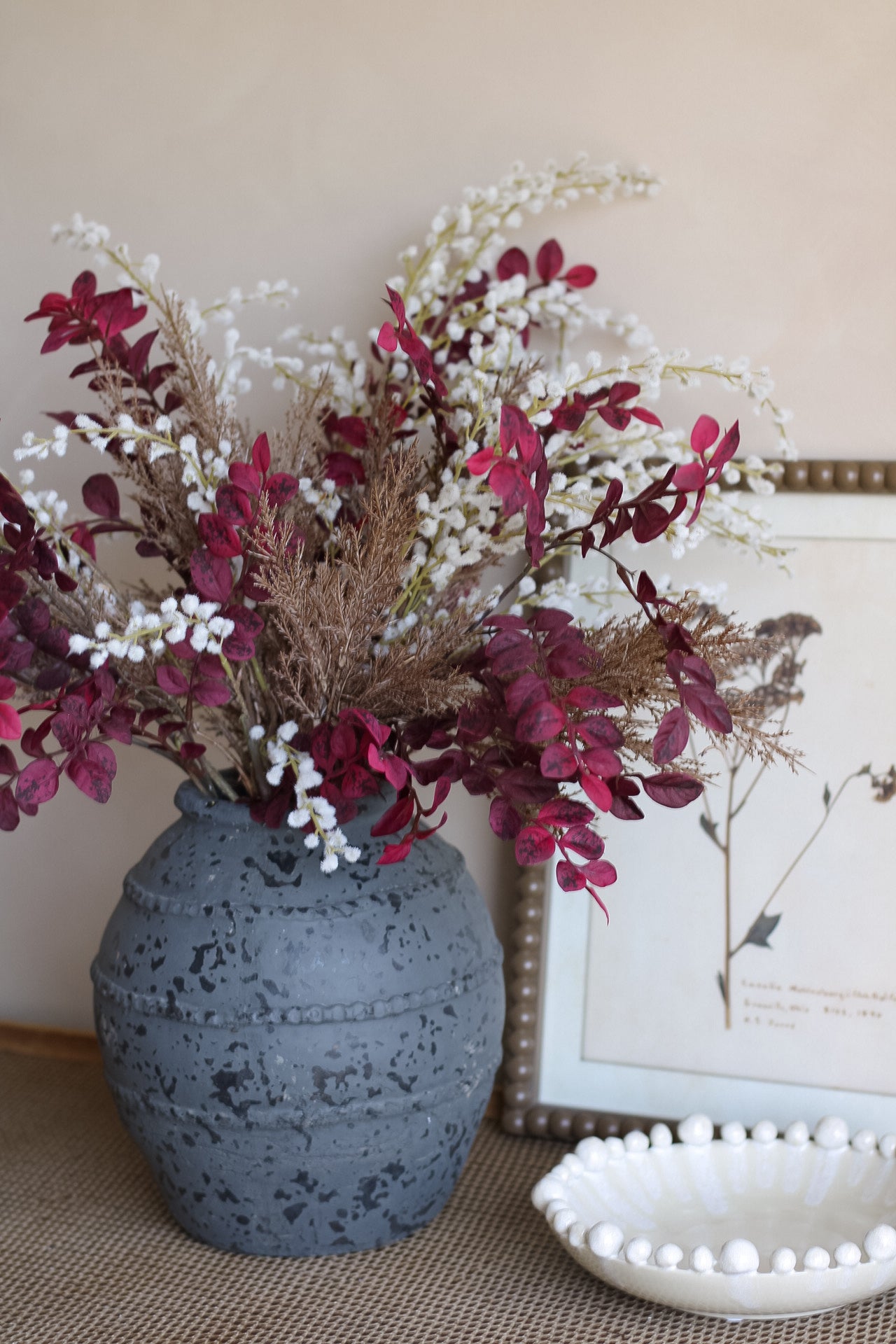 Charcoal textured vase with decorative autumn flowers on a surface with a blurred background