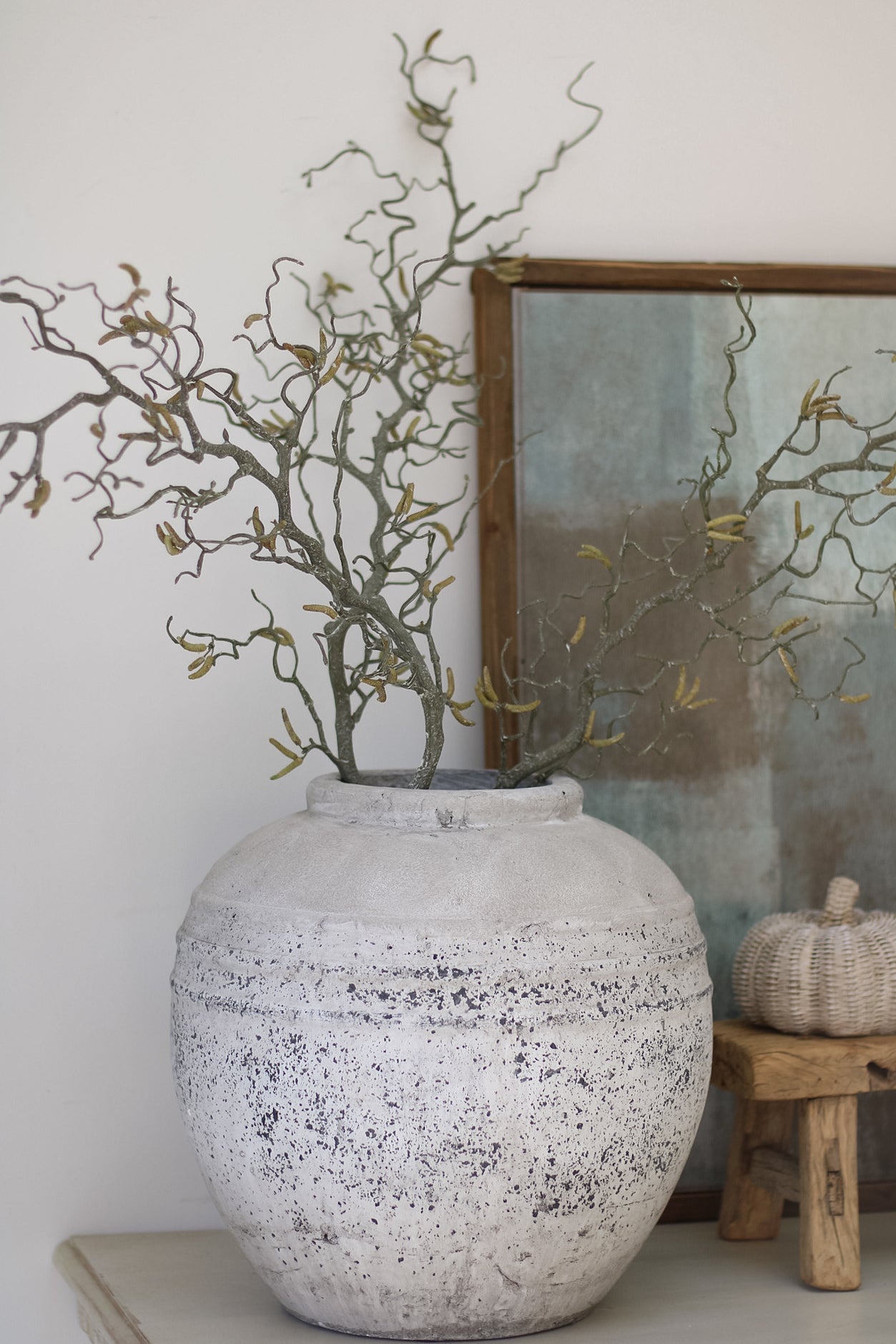 Decorative vase with branches on a shelf against a white wall