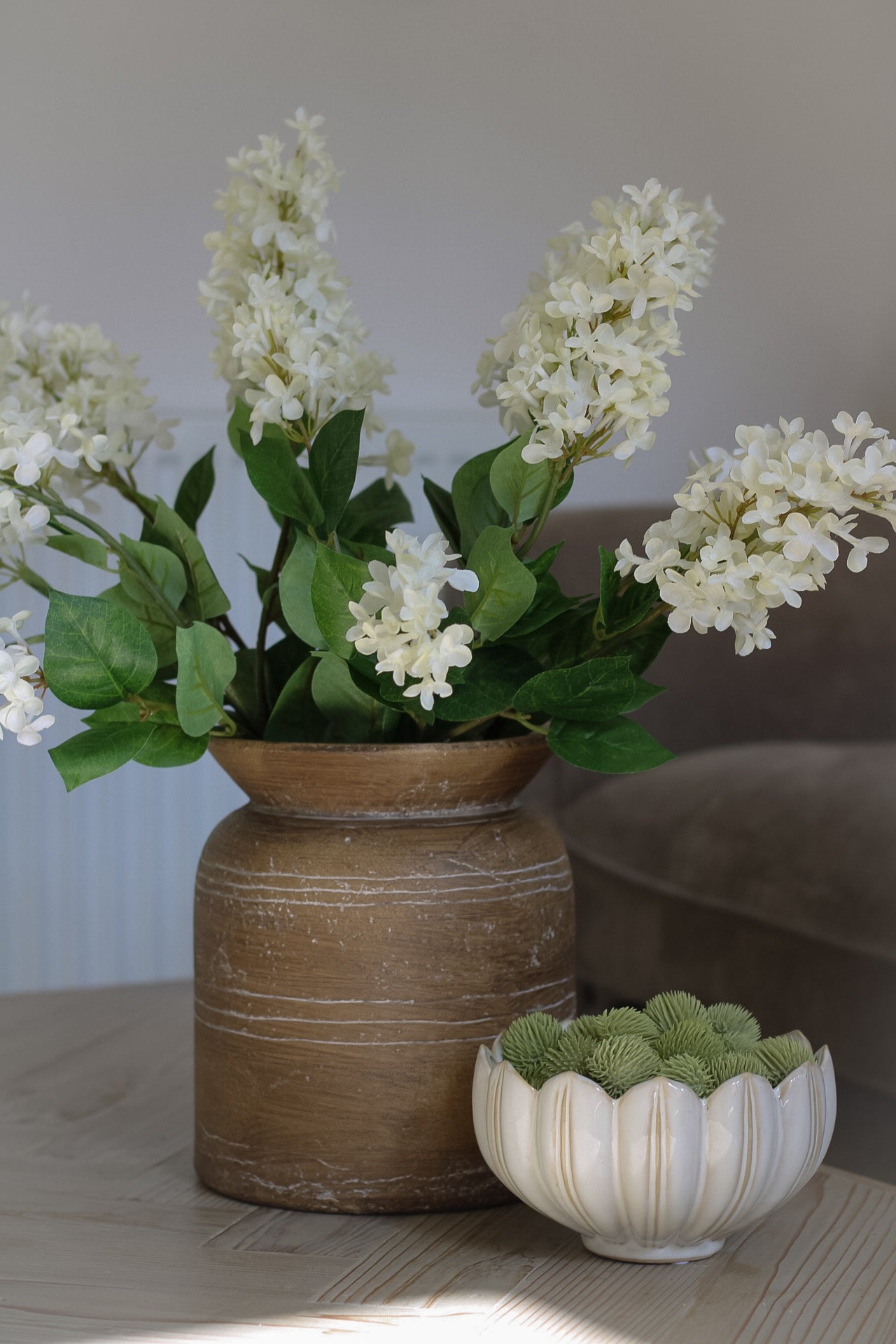 Faux bunch of cream lilac stems in brown rustic vase