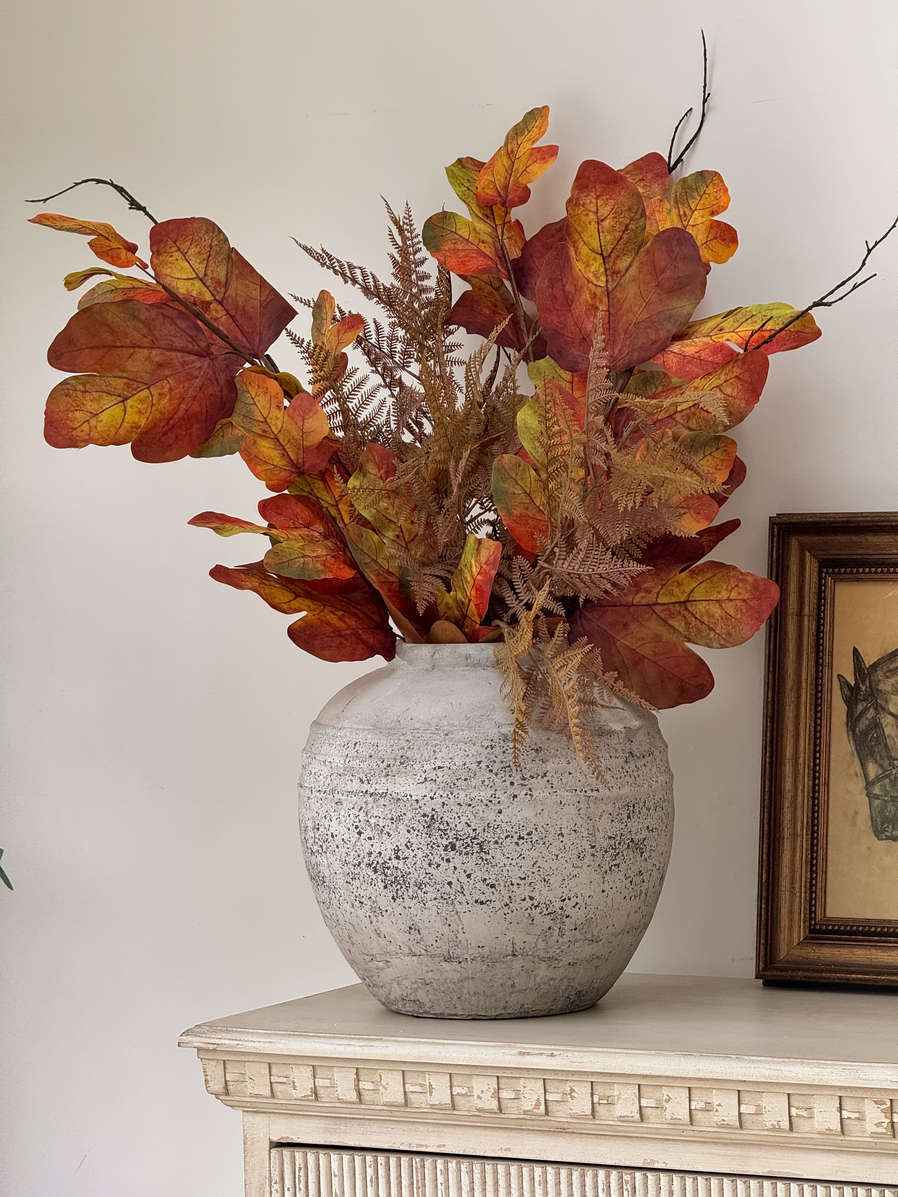 Decorative vase with autumn-themed leaves on a white surface