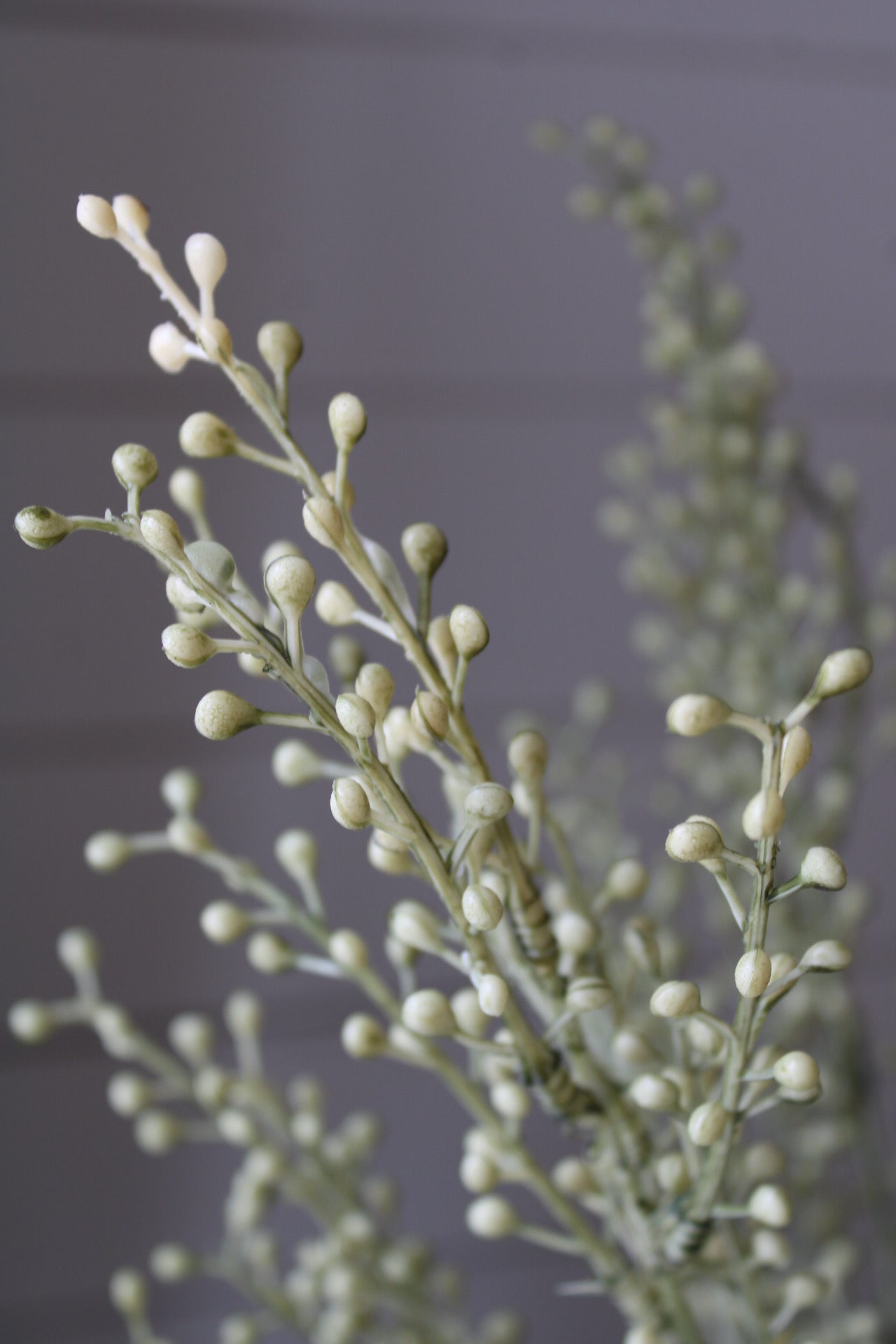 Close-up of a faux autumn branch with small buds against a neutral background