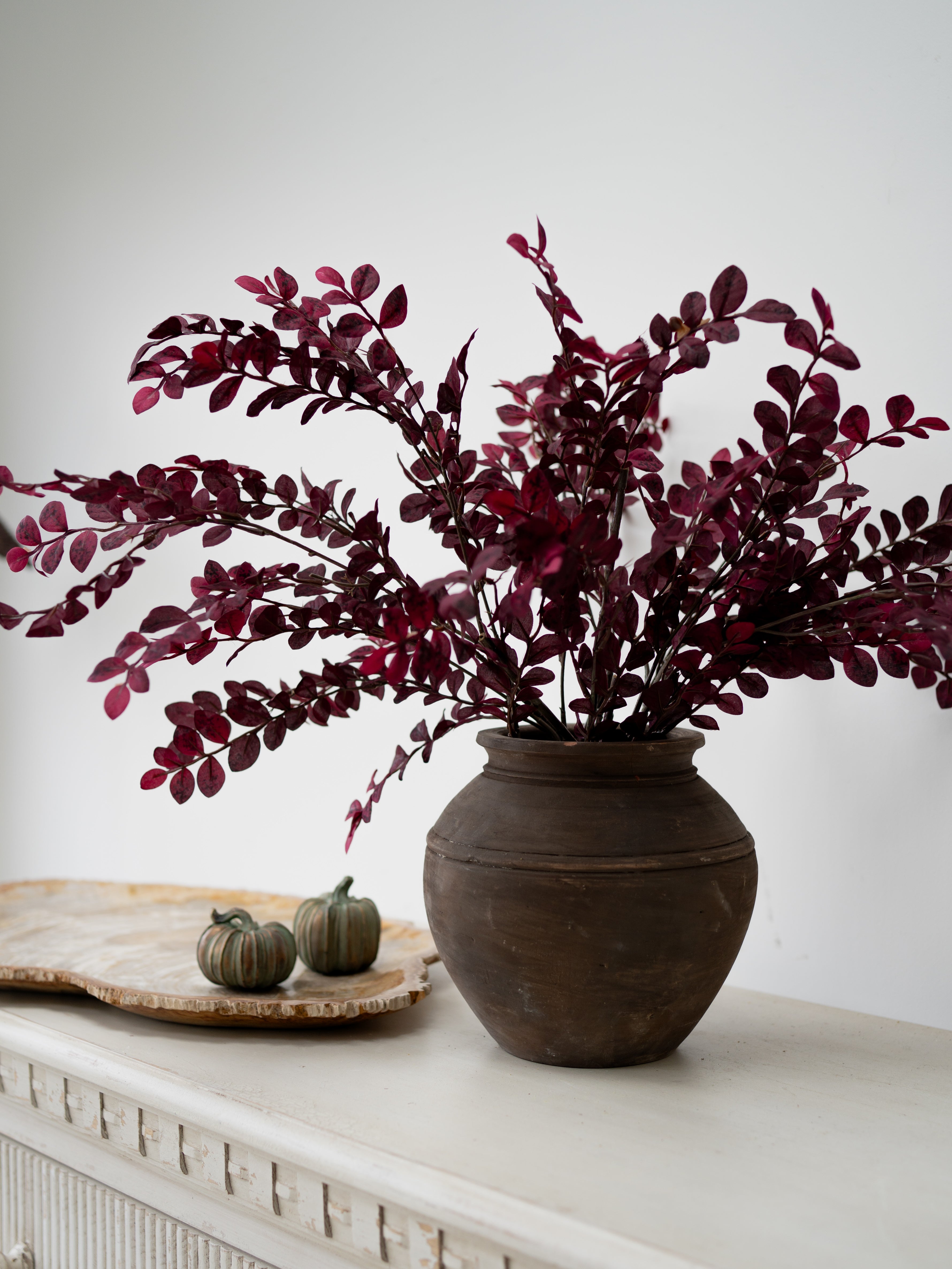 faux dark pink and red small plum leaves styled en masse in rustic brown vase