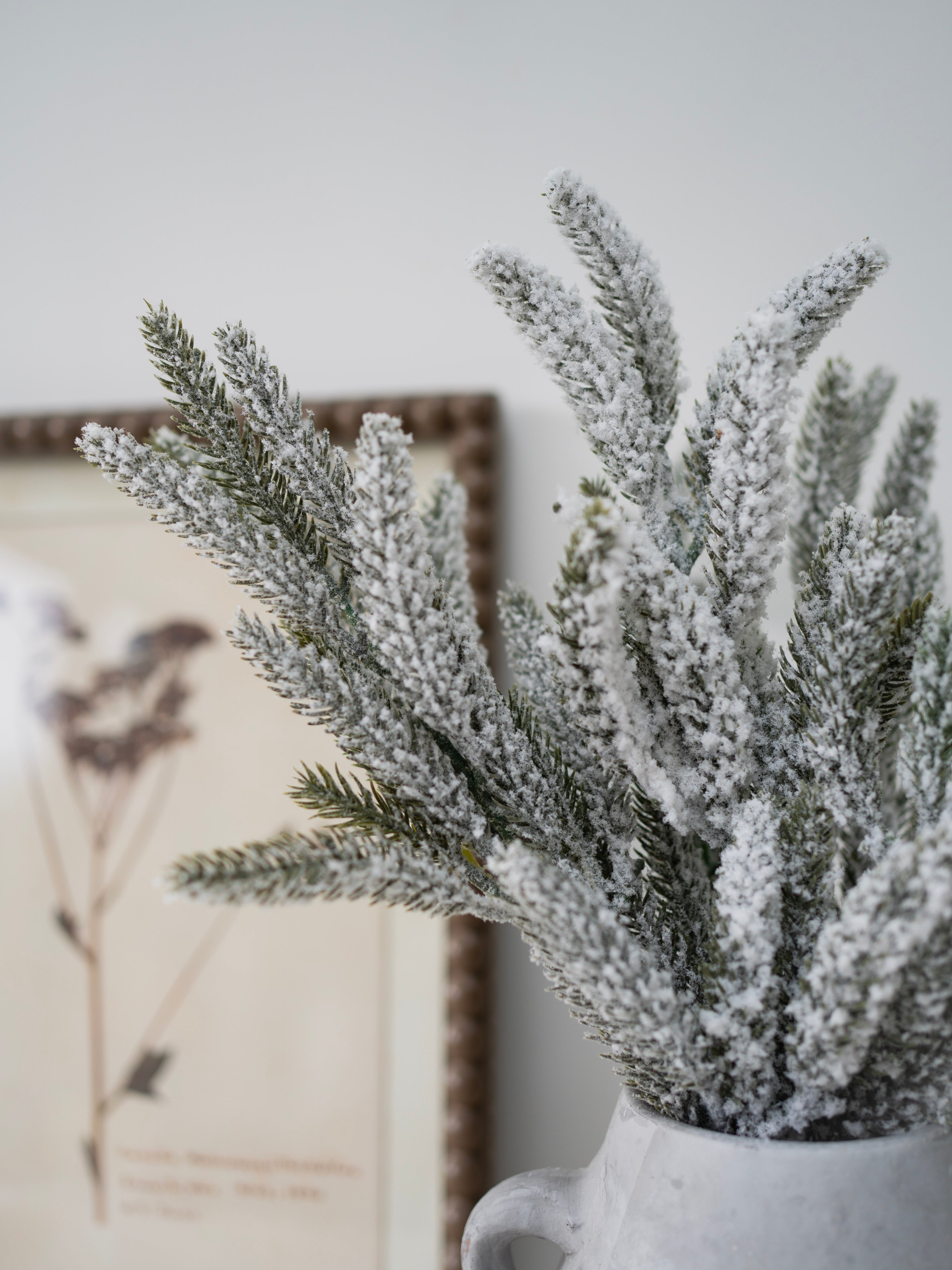 Frosted artificial plant in a white pot with a blurred background
