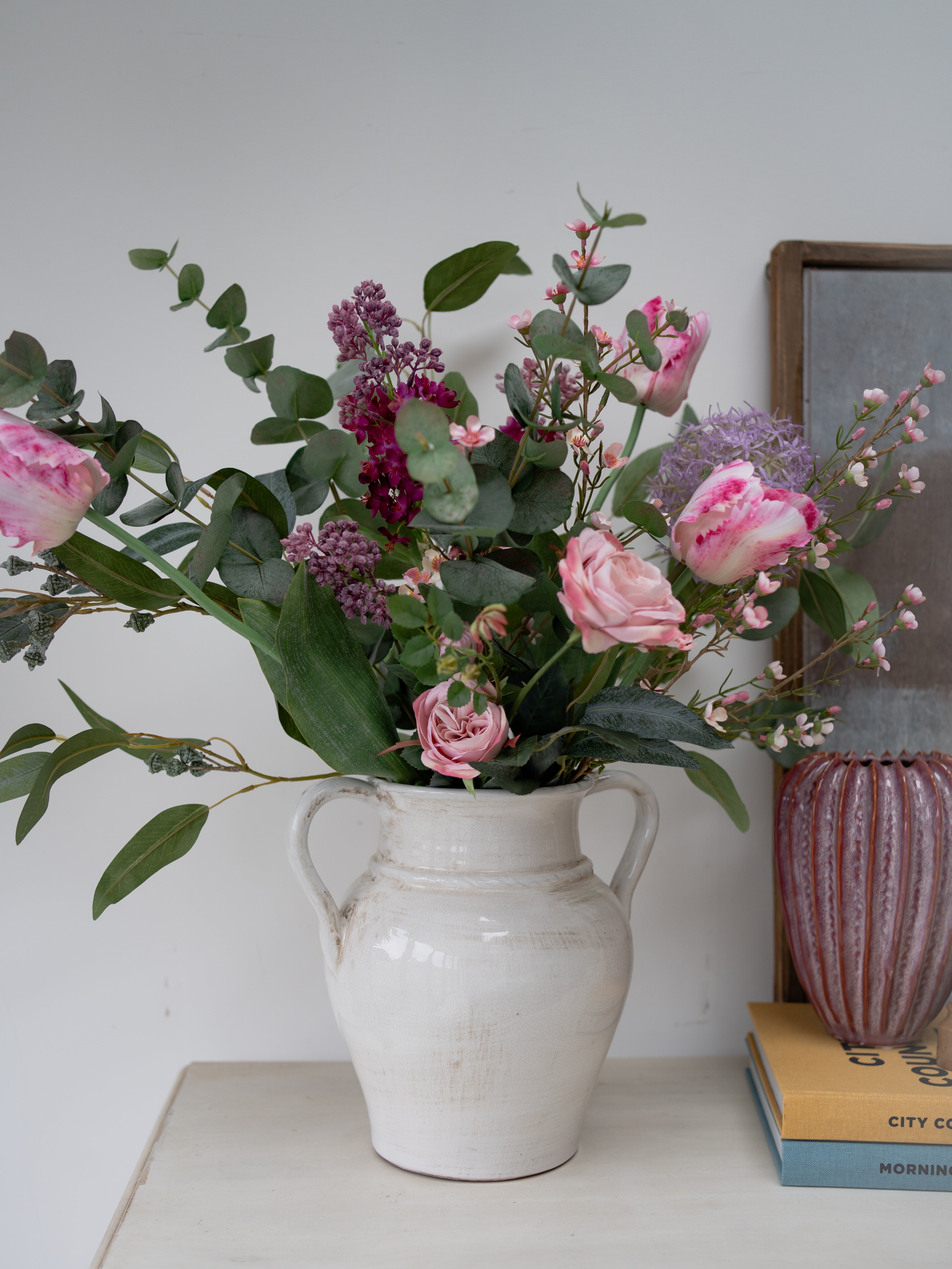 Floral arrangement in a white vase on a surface with a light background