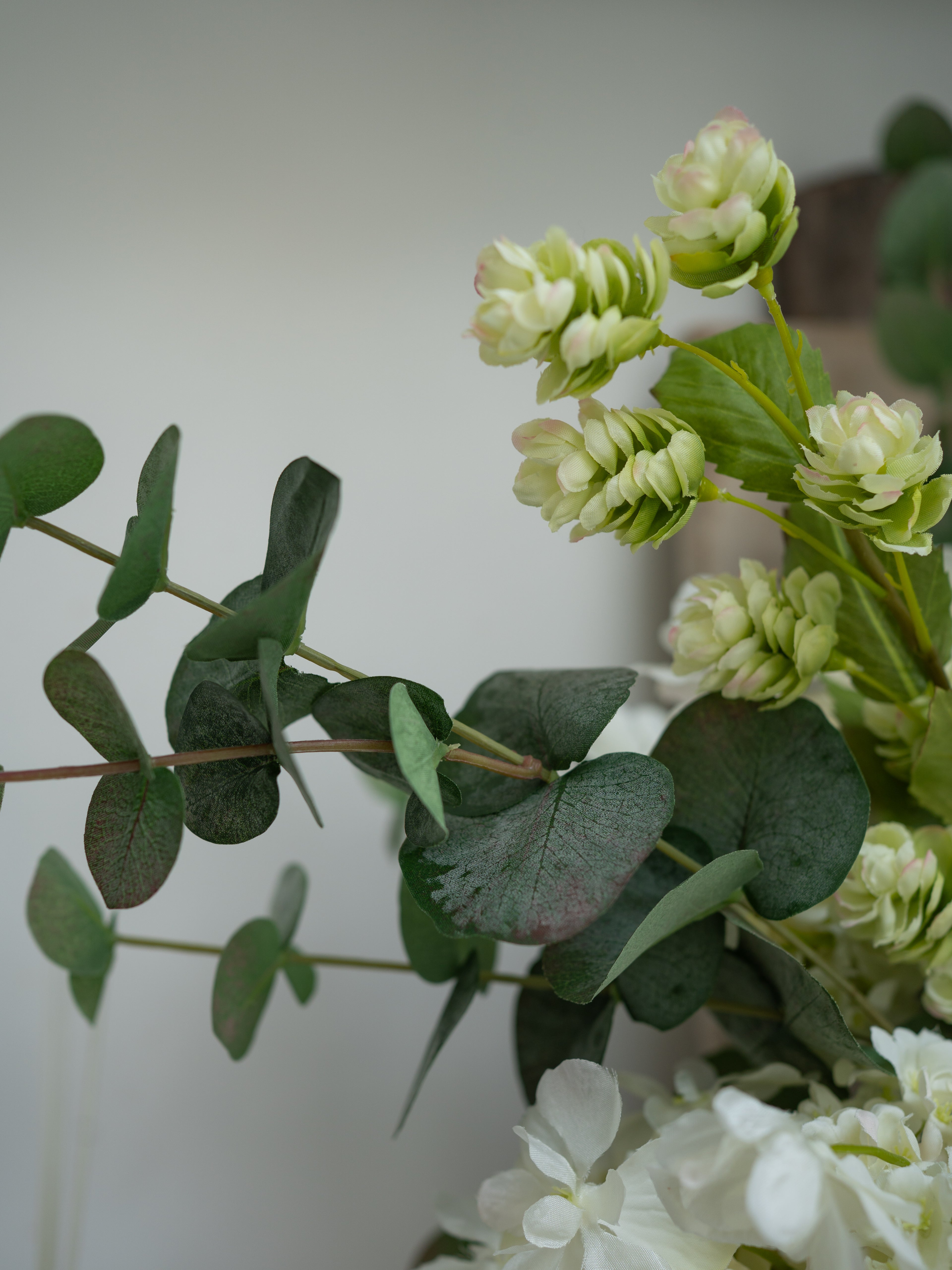 Close-up of green and white floral arrangement on a plain background