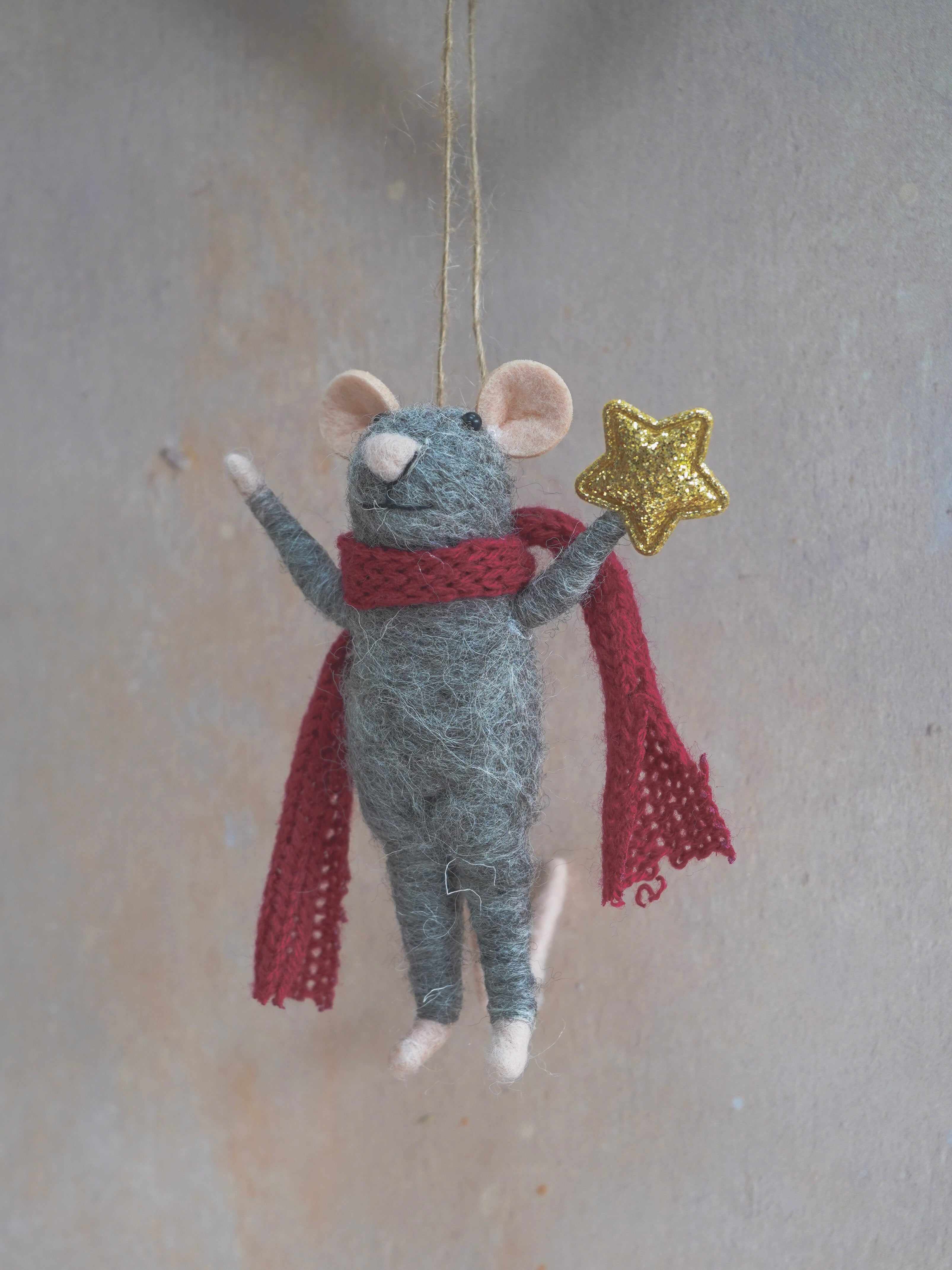 Decorative felt mouse ornament with a red scarf and gold star on a neutral background