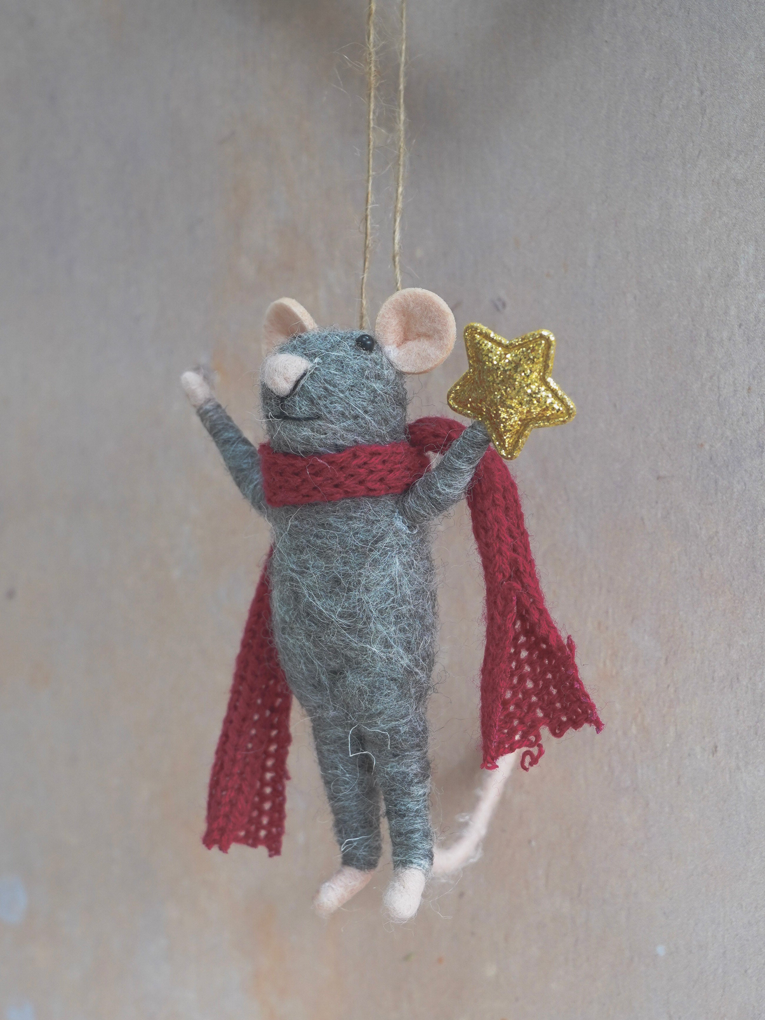 Decorative felt mouse ornament with a red scarf and gold star on a neutral background