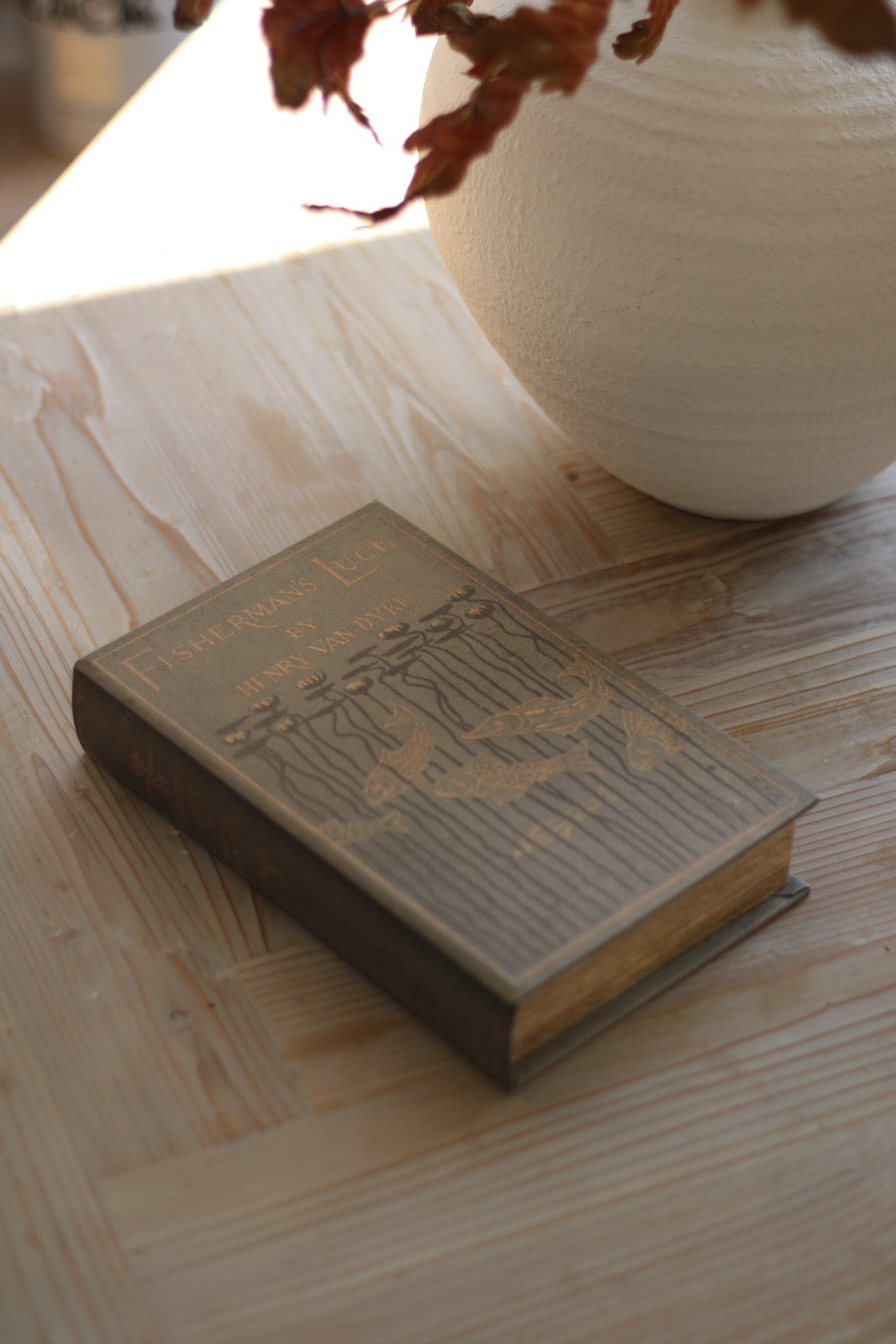 Vintage book on a wooden surface with a vase in the background