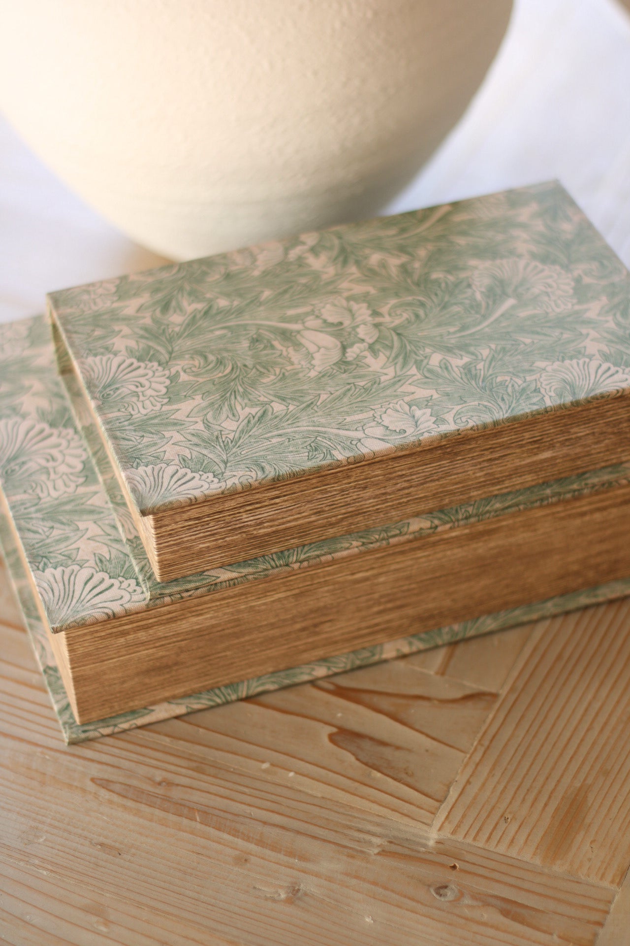 Wooden book boxes with floral patterned veneer on a wooden surface