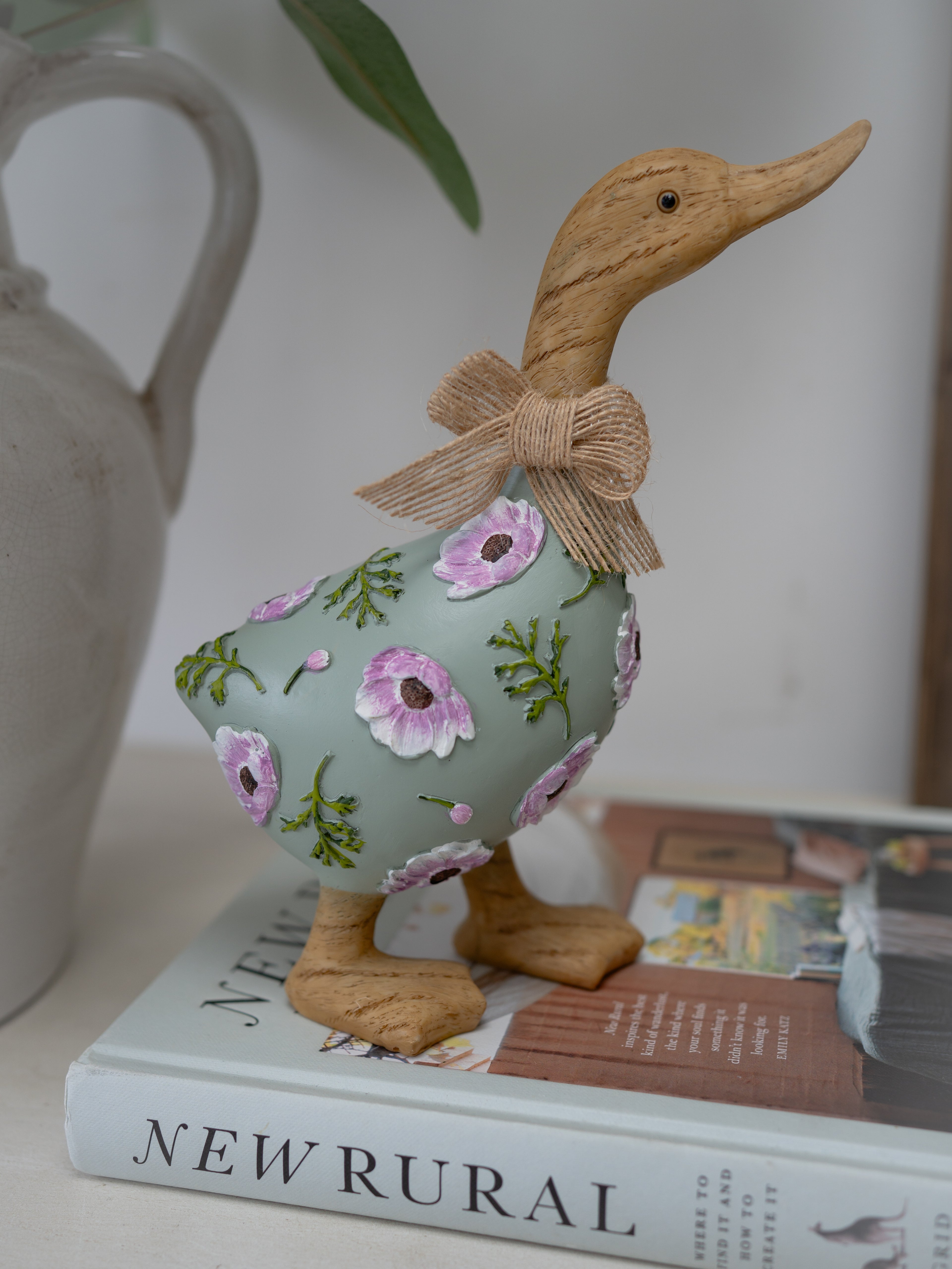 Decorative duck figurine with floral pattern and bow on a book