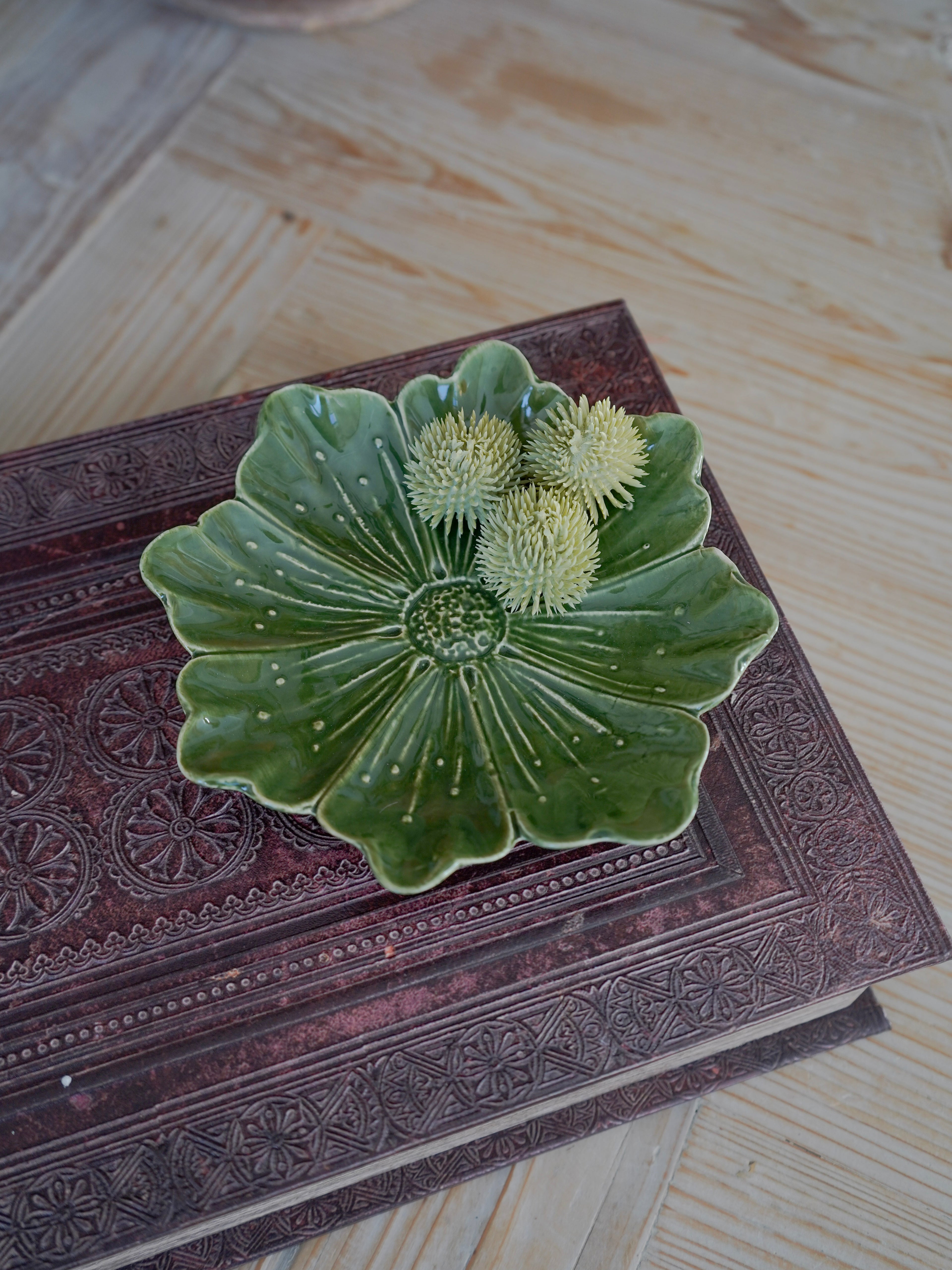 Green ceramic dish with floral design on a textured surface