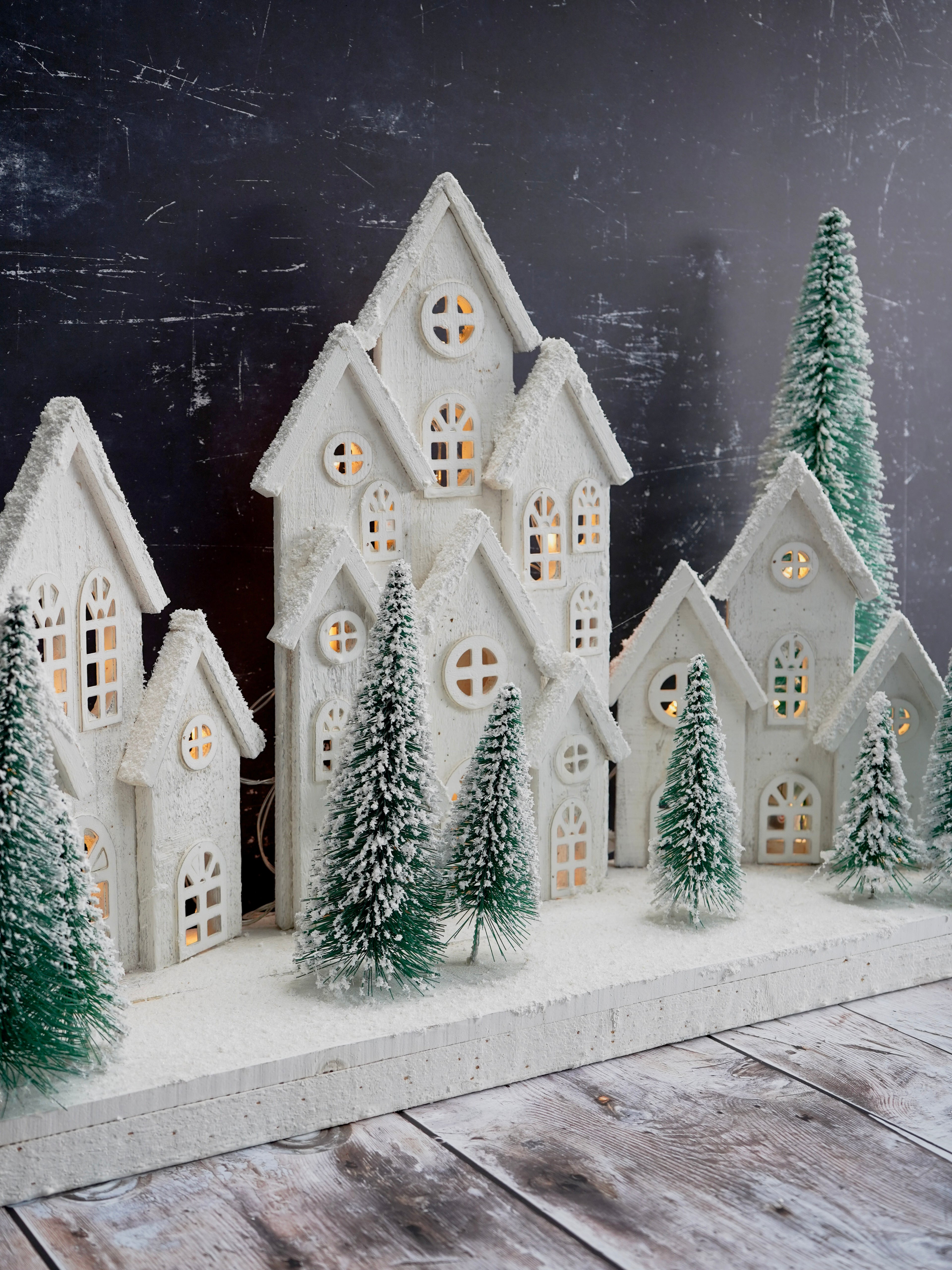 Decorative winter scene with miniature houses and trees on a dark background