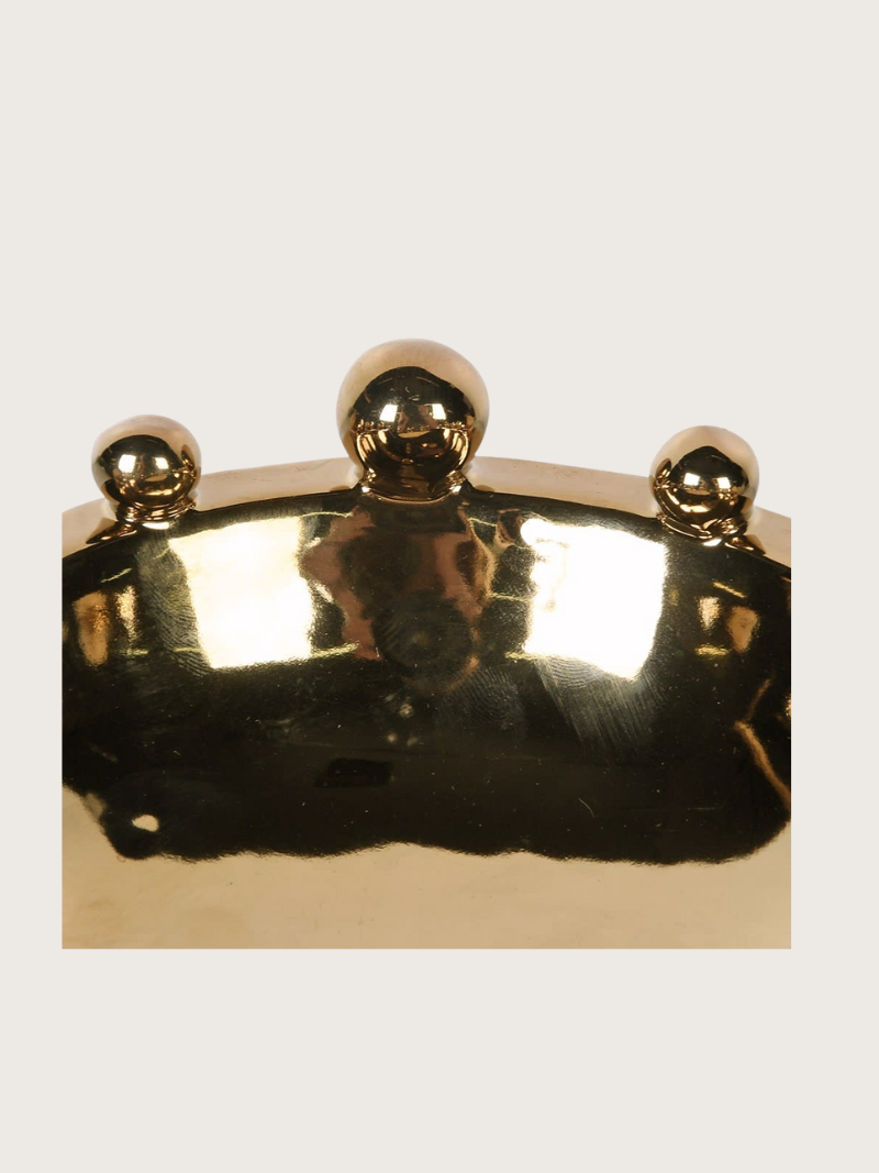 Gold bobble bowl with three spherical knobs on a light gray background
